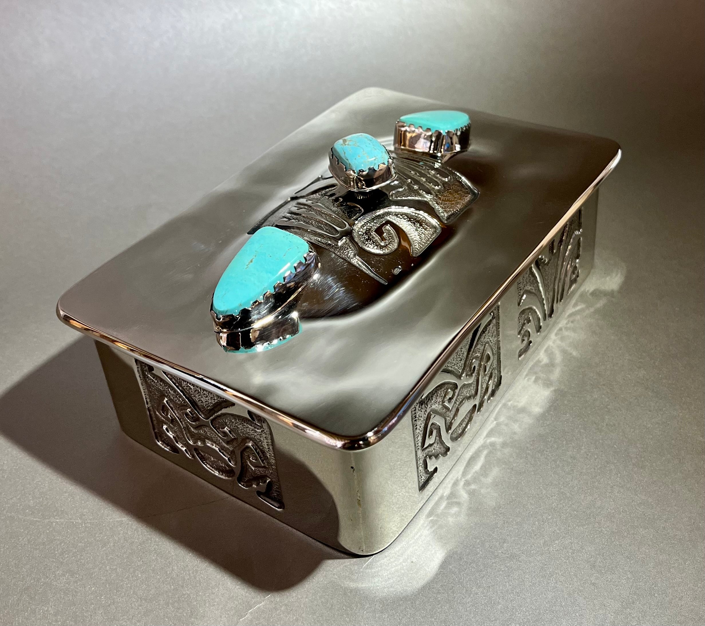 This Nickel Silver Treasure Chest features a stunning turquoise accent, hand-forged silver soldering, and an acid-etched design with luxurious leather lining. Approx. 6.5" x 4" x 2" deep. Nickel Silver Treasure Box w/ Turquoise