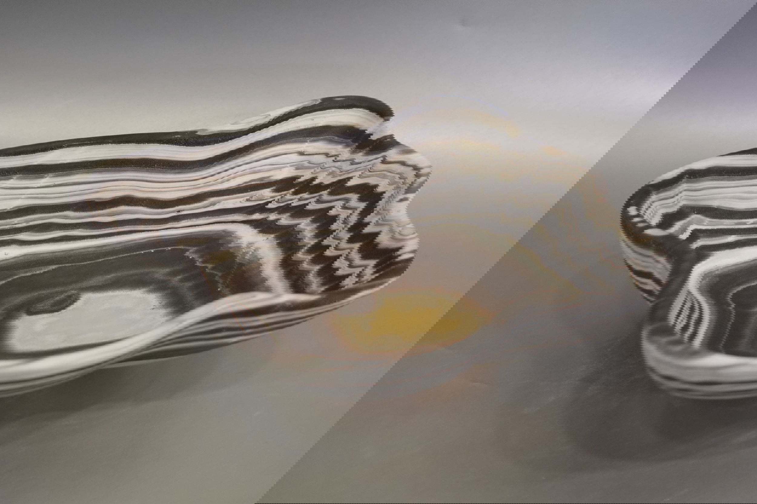 Indulge in the luxurious uniqueness of our Zebra Onyx Bowl. Its banded surface showcases the exquisite patterns of zebra onyx, while its distinct shape adds a touch of sophistication. Elevate your home decor with this exclusive piece that exudes elegance and refinement.Approx. 10.75" x 3" Zebra Onyx Bowl
