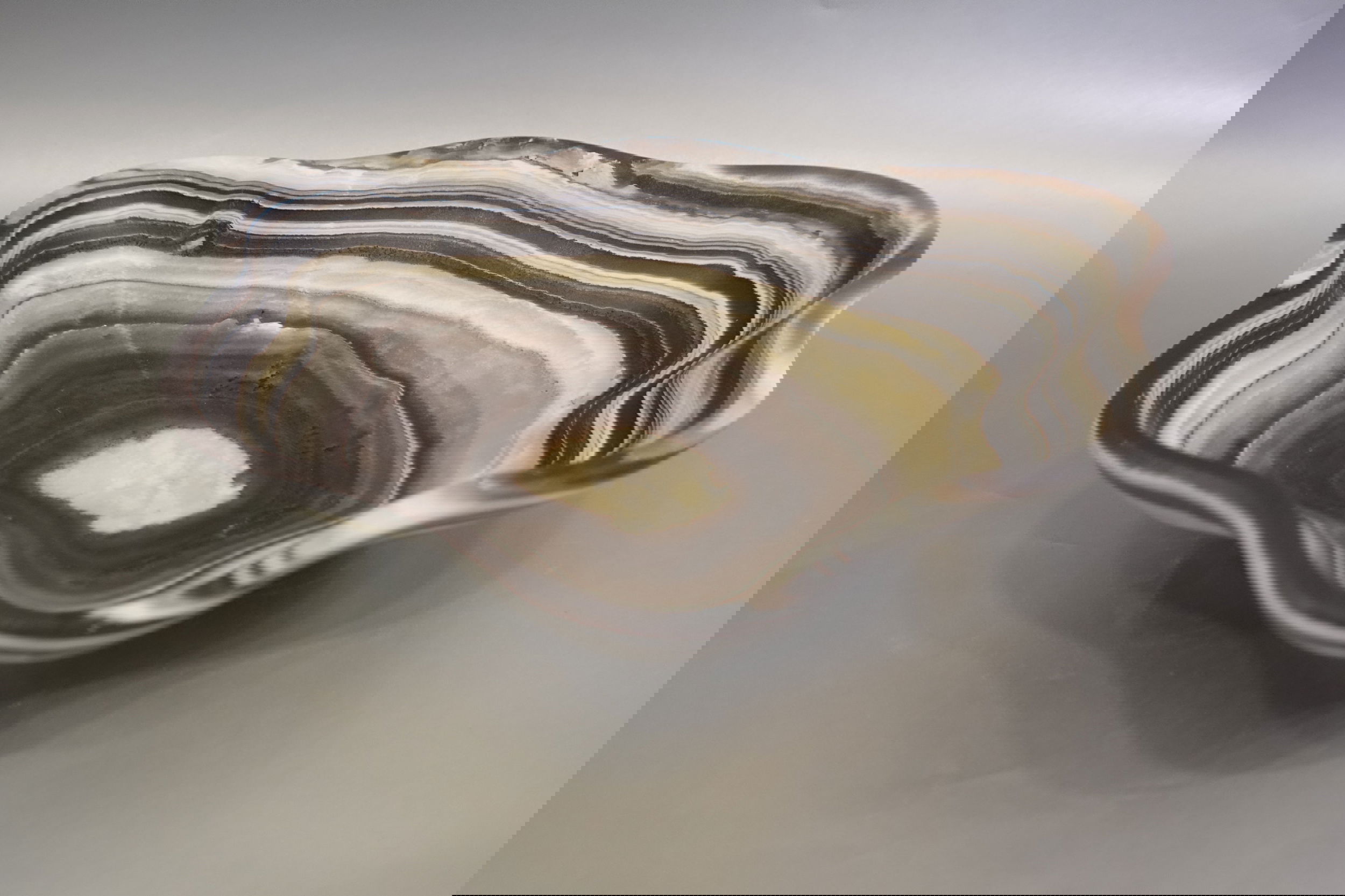 Indulge in the luxurious uniqueness of our Zebra Onyx Bowl. Its banded surface showcases the exquisite patterns of zebra onyx, while its distinct shape adds a touch of sophistication. Elevate your home decor with this exclusive piece that exudes elegance and refinement.Approx. 12" x 2.75" Zebra Onyx Bowl