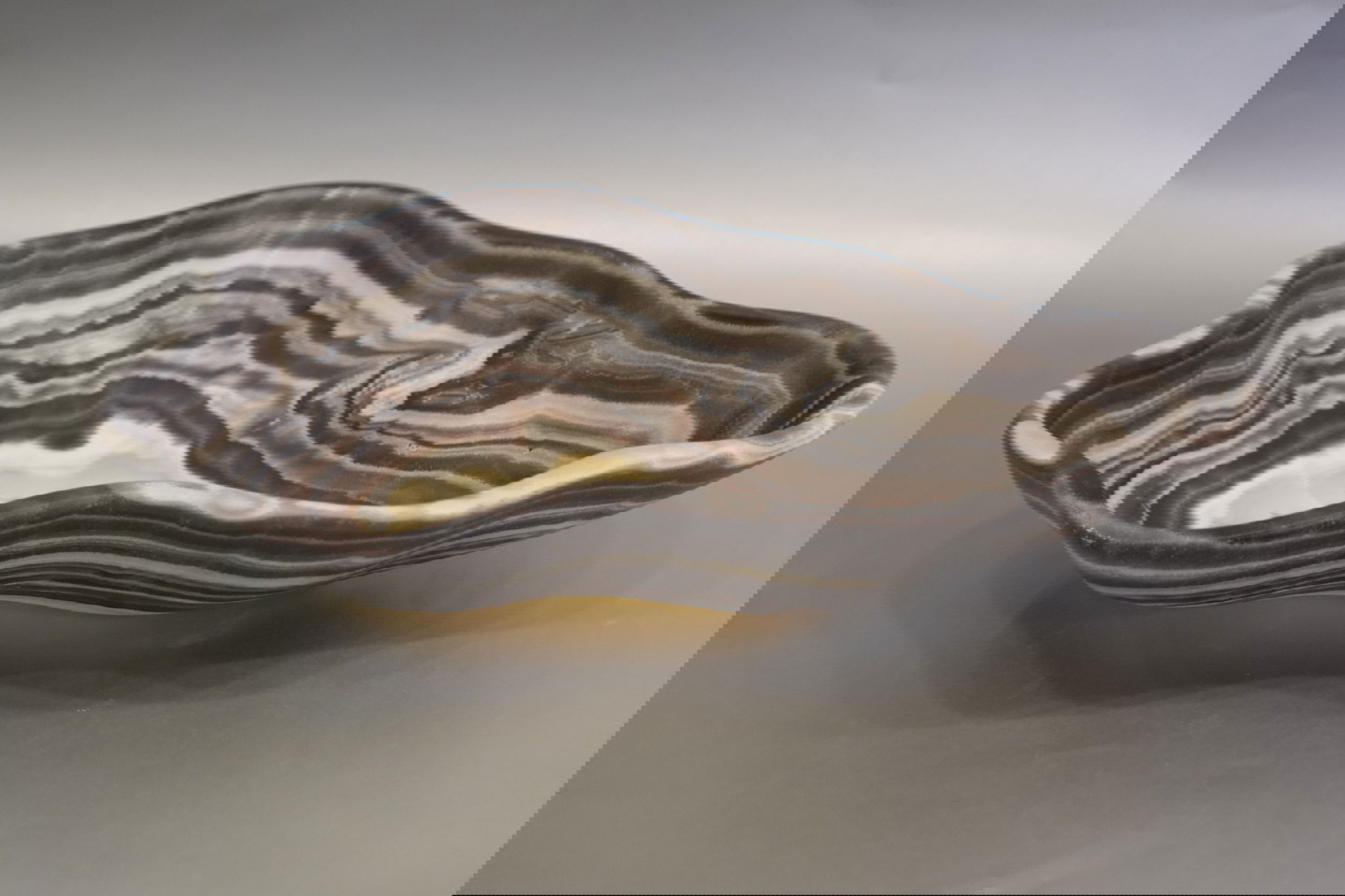 Indulge in the luxurious uniqueness of our Zebra Onyx Bowl. Its banded surface showcases the exquisite patterns of zebra onyx, while its distinct shape adds a touch of sophistication. Elevate your home decor with this exclusive piece that exudes elegance and refinement.Approx. 13" 2.75" Zebra Onyx Bowl