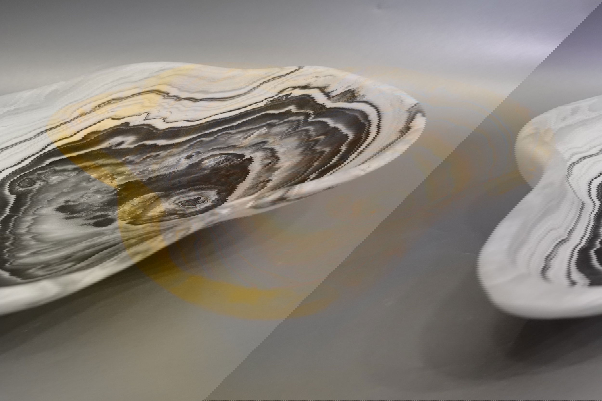 Indulge in the luxurious uniqueness of our Zebra Onyx Bowl. Its banded surface showcases the exquisite patterns of zebra onyx, while its distinct shape adds a touch of sophistication. Elevate your home decor with this exclusive piece that exudes elegance and refinement.Approx. 12" 3" Zebra Onyx Bowl