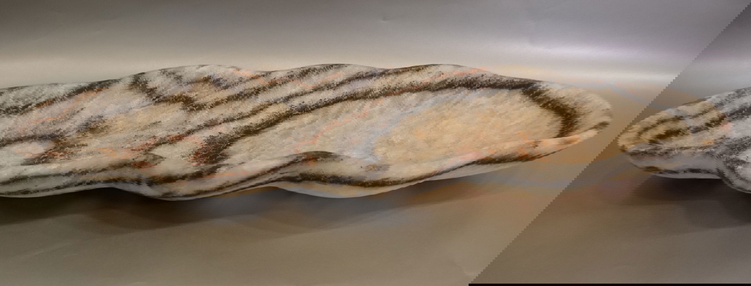 The Zebra Onyx Matte Trough is a luxurious addition to any space. Its stunning zebra onyx veining, combined with a sleek matte finish, creates a one-of-a-kind piece. With a freeform cut, this trough exudes exclusivity and elegance. Elevate your decor with this sophisticated and unique product.Approx. 28" x 10.25" x 3" Zebra Onyx Trough