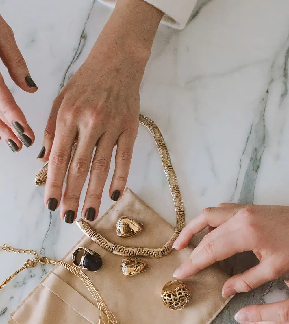 Hands showcasing gold rings and chains at Naifeh Fine Jewelry