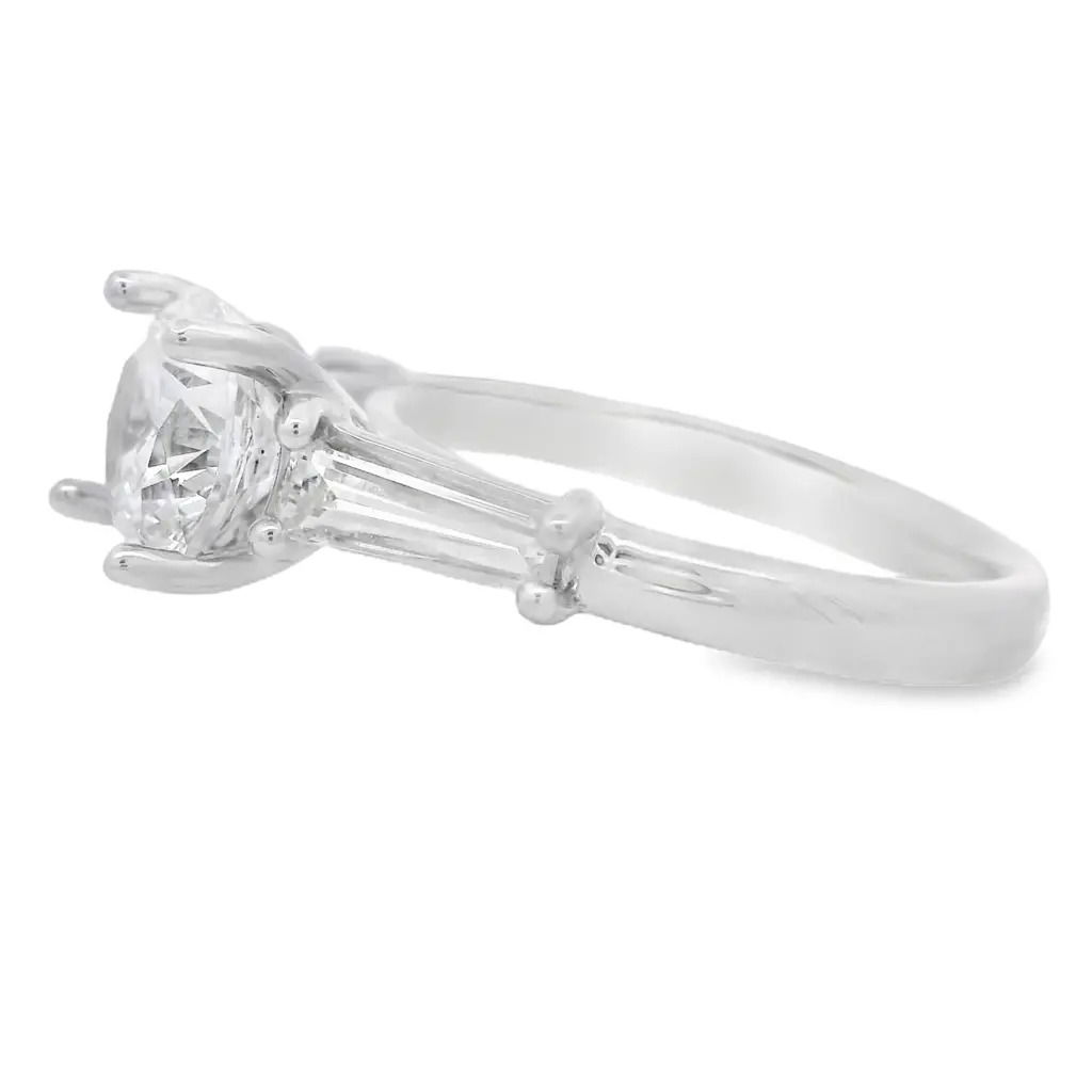 This three-stone semi-mount offers a refined, elegant setting for your center stone. Two sleek tapered baguette diamonds frame the center, adding symmetry and a touch of modern sophistication. Made for a 1.50 carat round stone (Center stone not included).-18k White gold-Baguette diamonds, 0.63cts-Size 6.5, Contact for sizing optionsItem# 140-00229 Three-Stone Semi-Mount