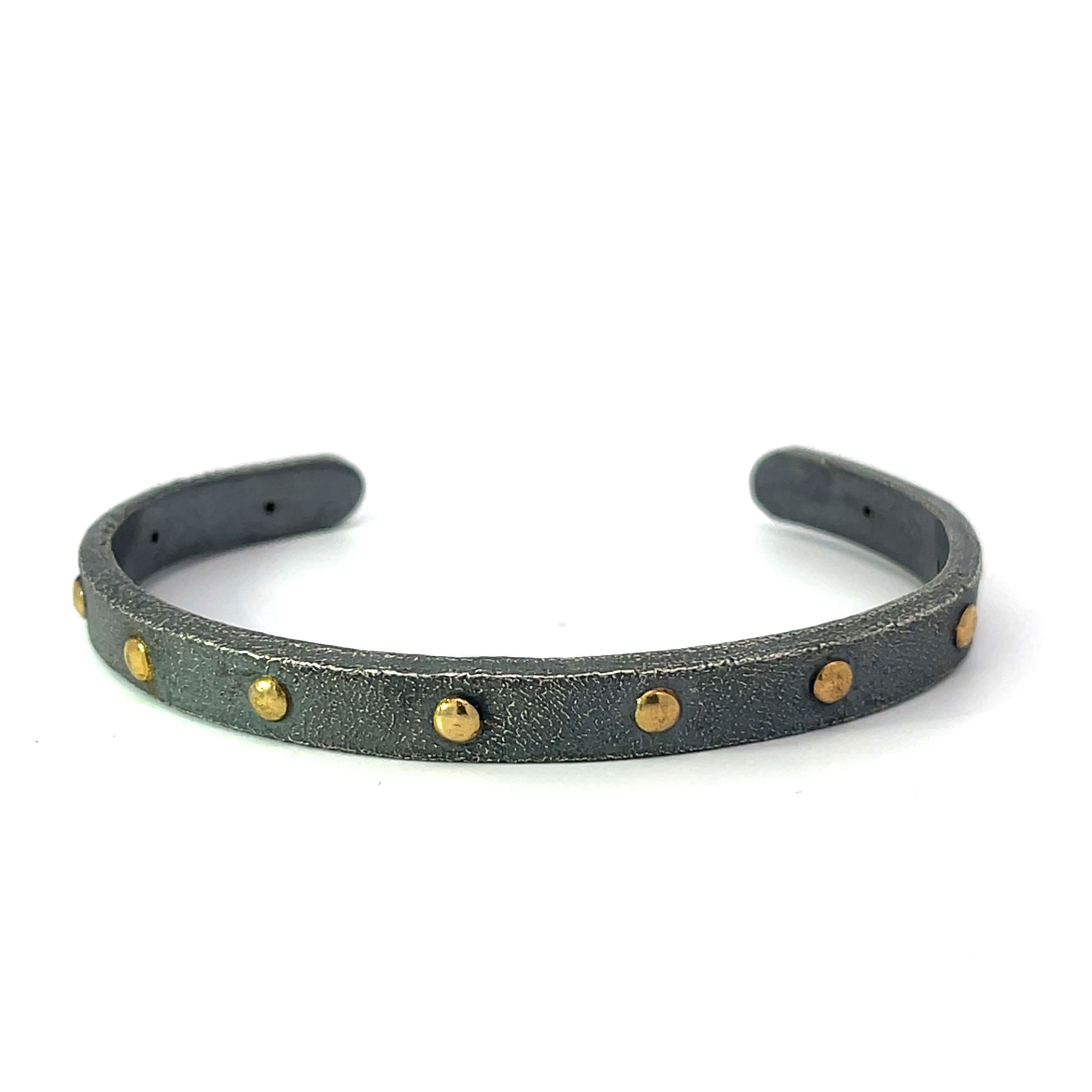 This cuff features a bold, textured finish that highlights its raw, artisanal character. Accented with gold details, it creates a striking contrast that blends modern elegance with a rugged, contemporary edge.-22k Yellow gold-Oxidized stainless steelItem# 610-2000004 Oxidized Sterling Silver Cuff With Gold Accents