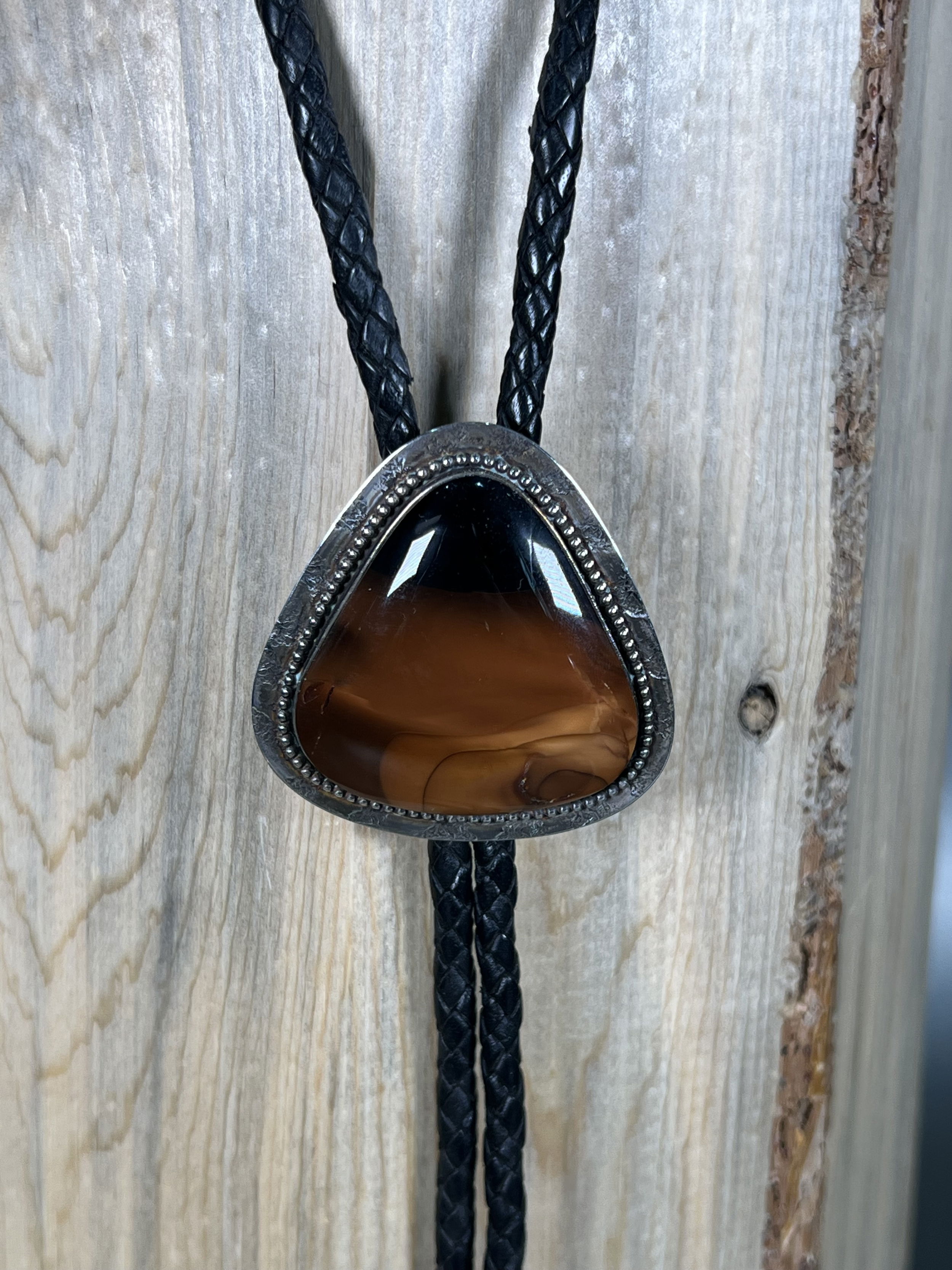 Elevate your style with our Black Sky Bruneau Jasper Bolo. Hand-crafted locally, this unique bolo tie features a stunning Idaho Bruneau Jasper stone set in sleek, silver hardware. Add a touch of sophistication to any outfit with this luxurious accessory that will surely make a statement.-Sterling silver-Jasper-LeatherItem# 27675192 Black Sky Bruneau Jasper Bolo