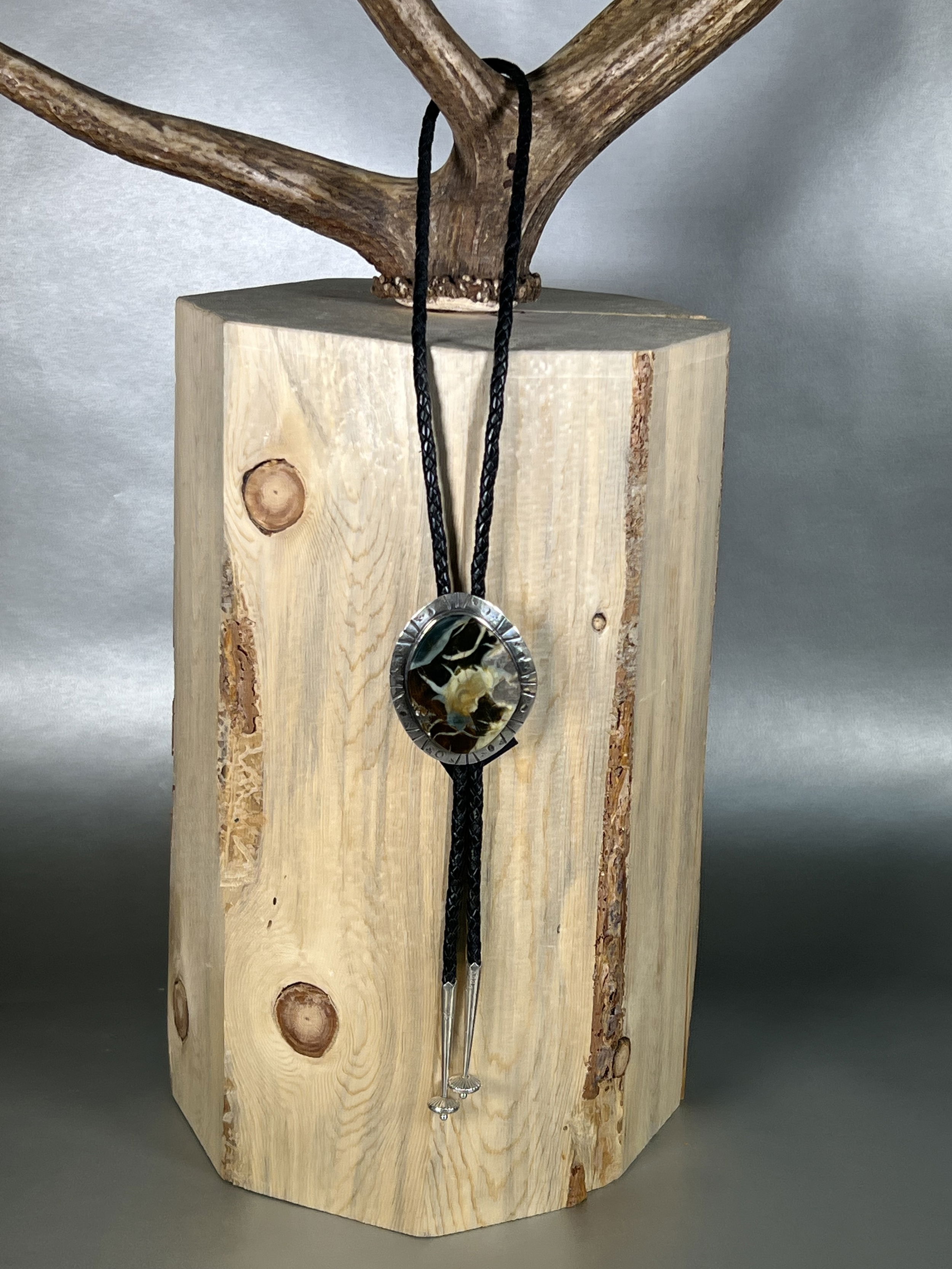 Elevate your style with our Blue Beard Dragon Jasper Bolo. Hand-crafted locally, this unique bolo tie features a stunning Oregon Morrisonite Jasper stone set in sleek, silver hardware. Add a touch of sophistication to any outfit with this luxurious accessory that will surely make a statement.-Sterling silver-Jasper-LeatherItem# 63063608 Blue Beard Dragon Jasper Bolo