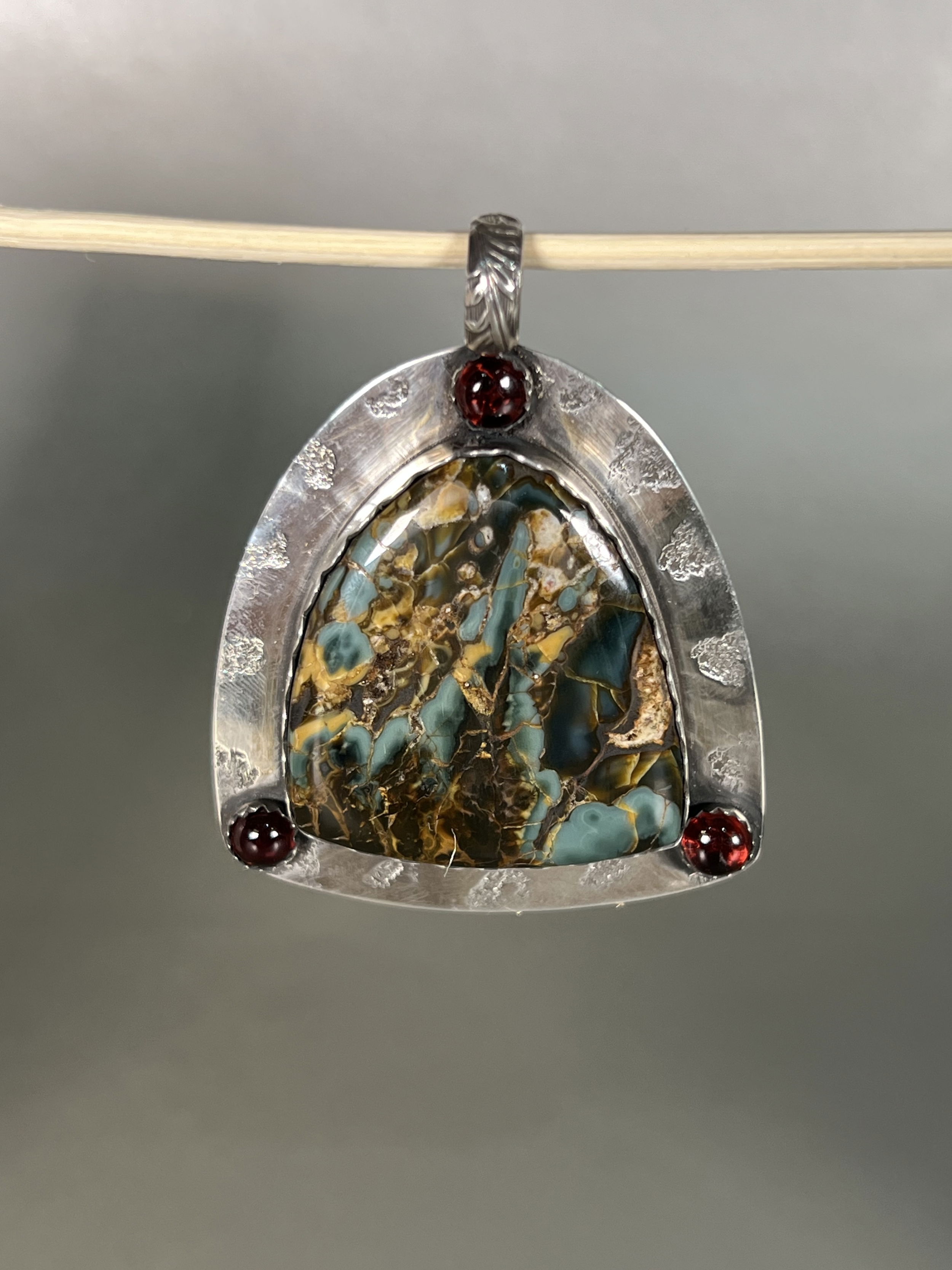 Indulge in the natural beauty of the Midnight Dancing Blues Plume Agate Pendant. With agate mined and hand-crafted locally in Sun Valley Idaho, this one-of-a-kind piece boasts intricate details and a luxurious aesthetic. Elevate your style with this exclusive pendant and embrace the artistry and authenticity of local craftsmanship. Includes the Midnight Blue Plume with 3 matching Garnets.-Sterling silver-Agate-GarnetItem# 91335480 Midnight Dancing Blues Plume Agate Pendant