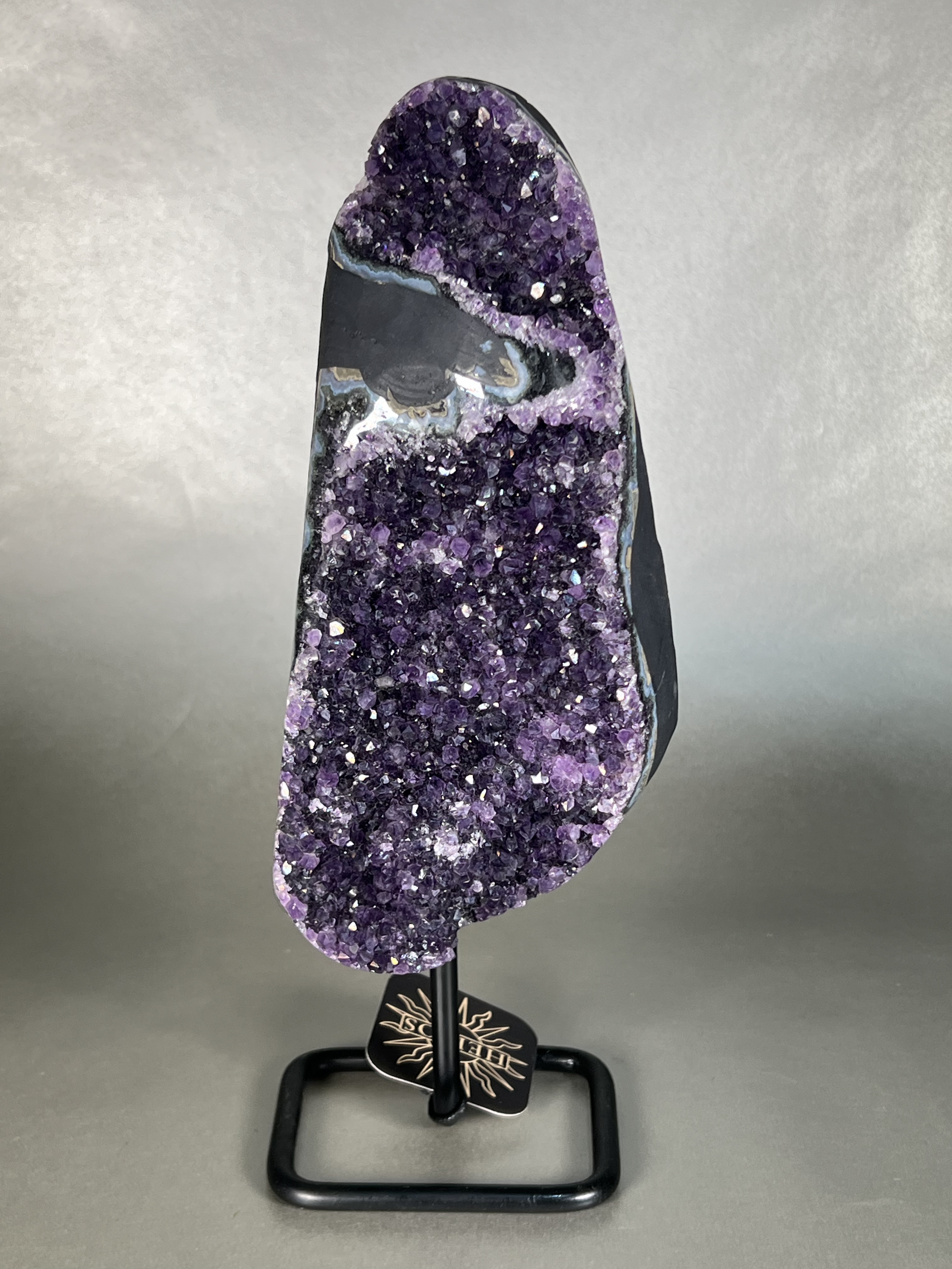 This amethyst on stand is the perfect addition to any home decor. Crafted with a premium natural amethyst crystal specimen and sturdy stand, this piece is sure to add a touch of elegance to any room. Its unparalleled beauty and durability make it a perfect long-term home accessory. Approx. 4" x 12" Uruguayan Amethyst On Stand