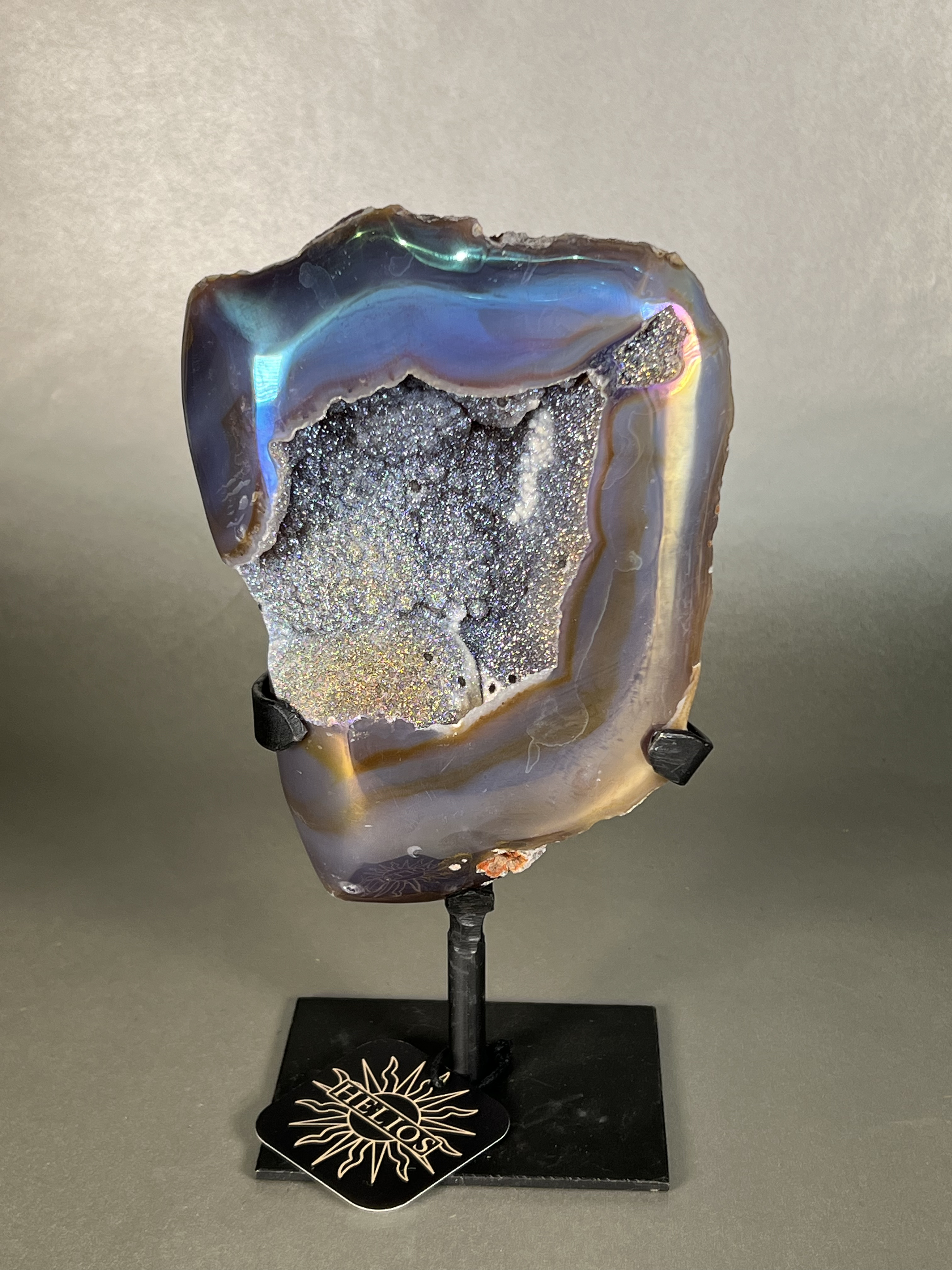 Experience the dreamy elegance of our Aura Agate Obelisk. Each one is uniquely crafted to exude a sense of luxury and exclusivity. Featuring the rare Aura Agate stone, this obelisk brings a touch of sophistication and beauty to any space. Elevate your decor with this truly one-of-a-kind piece. Approx. 5"x9" Aura Agate Geodes On Stand
