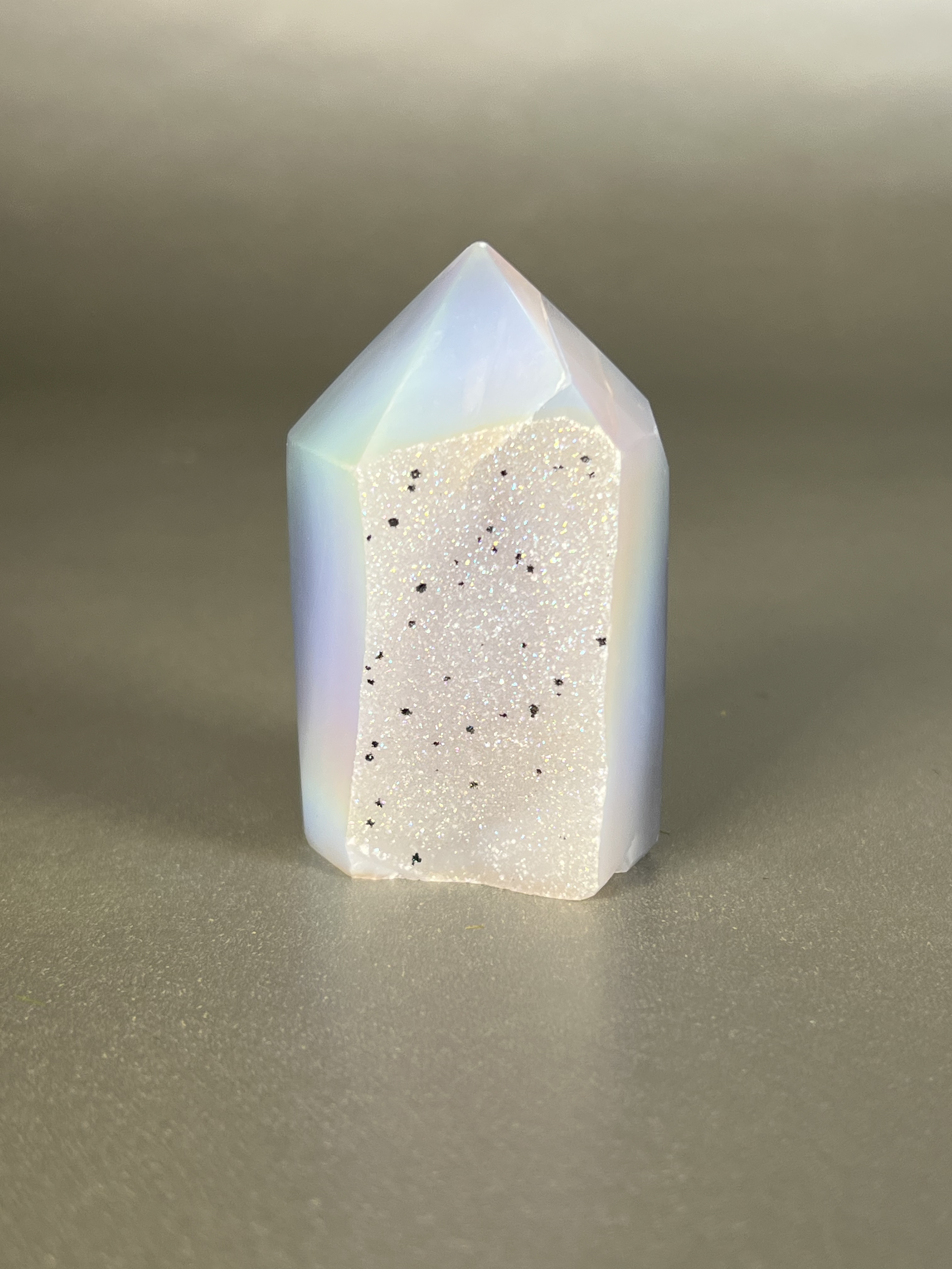 Experience the dreamy elegance of our Aura Agate Obelisk. Each one is uniquely crafted to exude a sense of luxury and exclusivity. Featuring the rare Aura Agate stone, this obelisk brings a touch of sophistication and beauty to any space. Elevate your decor with this truly one-of-a-kind piece. Approx. 1.5" x 3" Aura Agate Tower