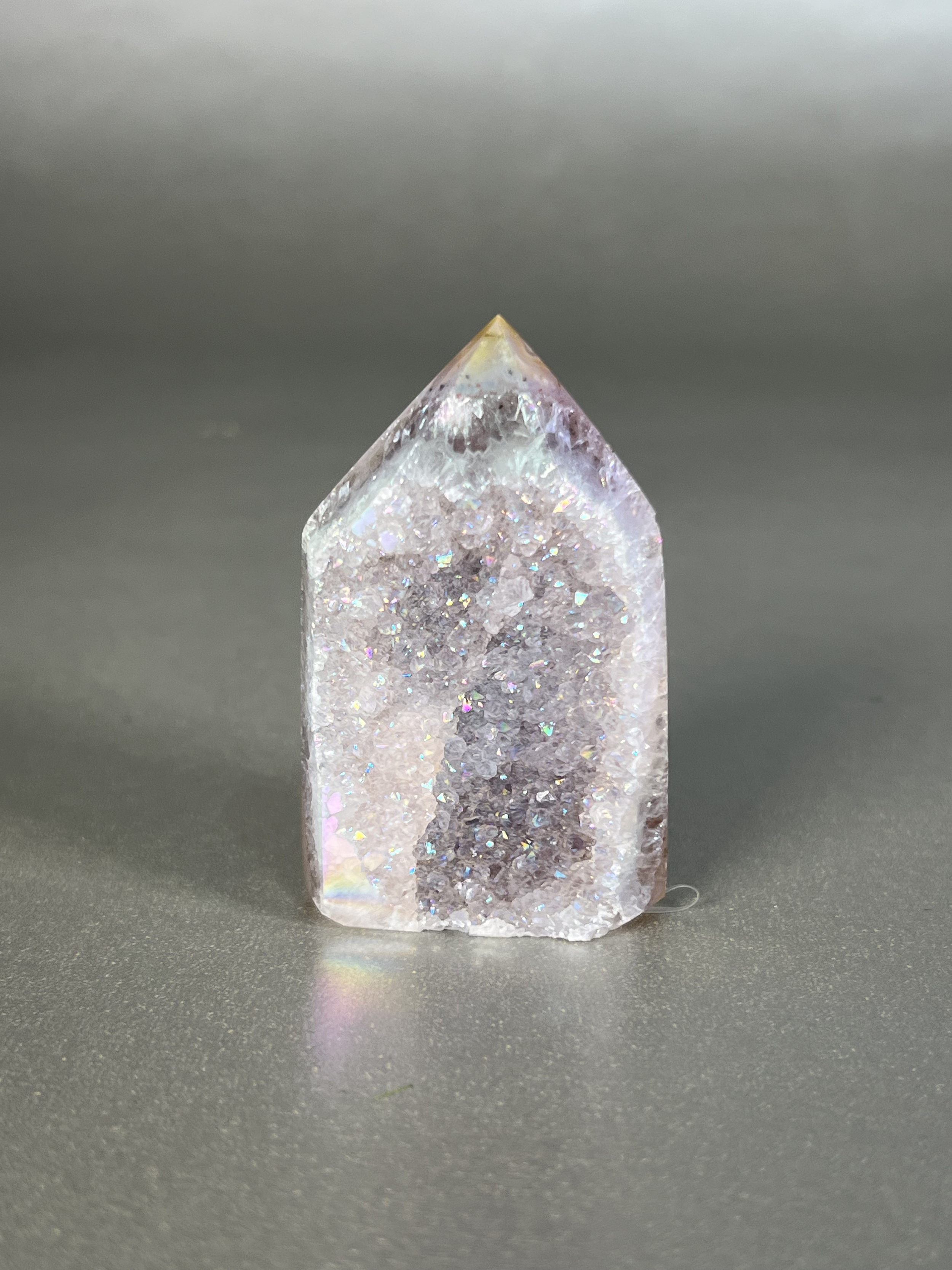 Experience the dreamy elegance of our Aura Agate Obelisk. Each one is uniquely crafted to exude a sense of luxury and exclusivity. Featuring the rare Aura Agate stone, this obelisk brings a touch of sophistication and beauty to any space. Elevate your decor with this truly one-of-a-kind piece. Approx. 1.5" x 2.5" Aura Agate Tower