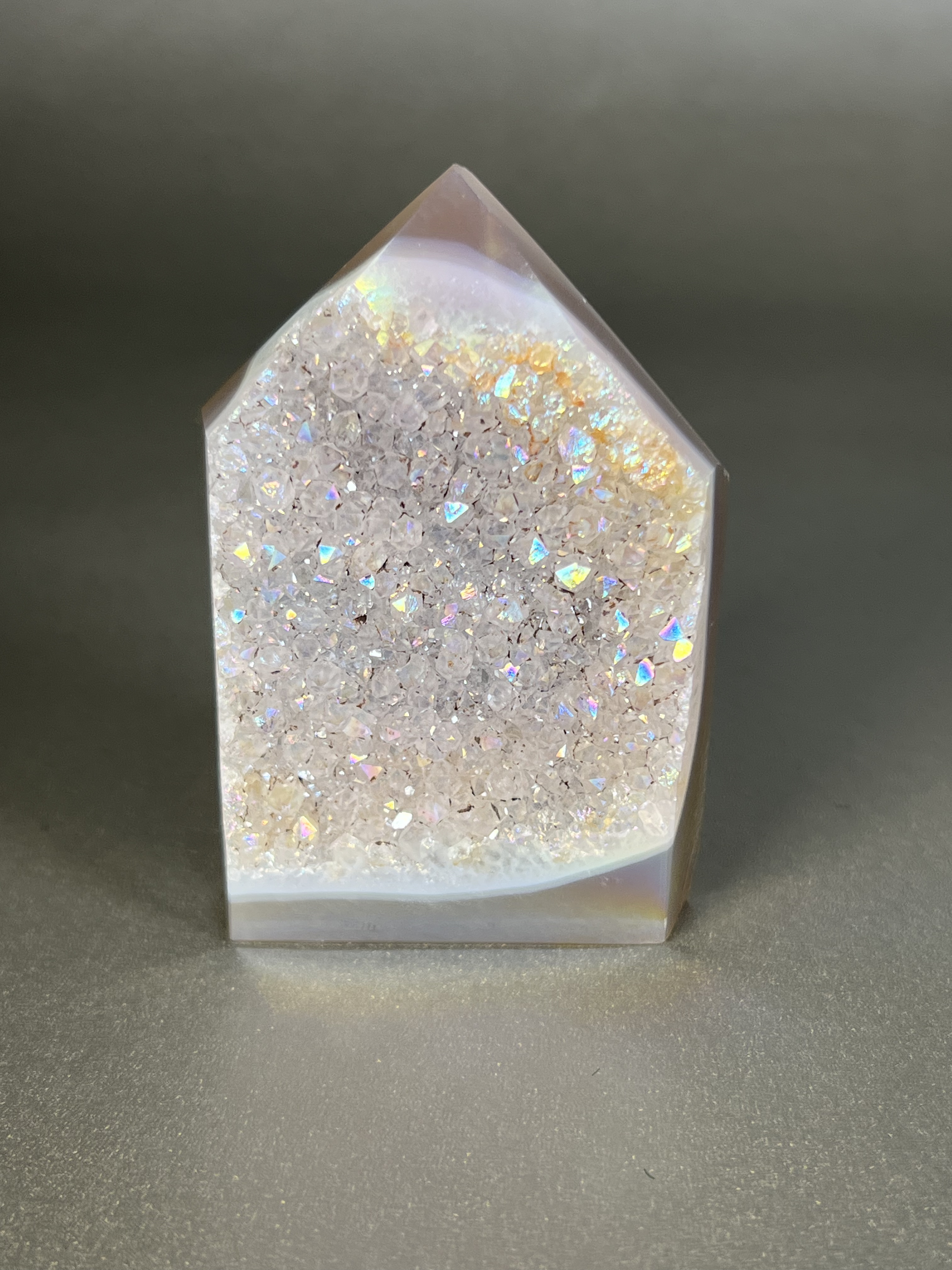 Experience the dreamy elegance of our Aura Agate Obelisk. Each one is uniquely crafted to exude a sense of luxury and exclusivity. Featuring the rare Aura Agate stone, this obelisk brings a touch of sophistication and beauty to any space. Elevate your decor with this truly one-of-a-kind piece. Approx. 2" x 3.5" Aura Agate Tower