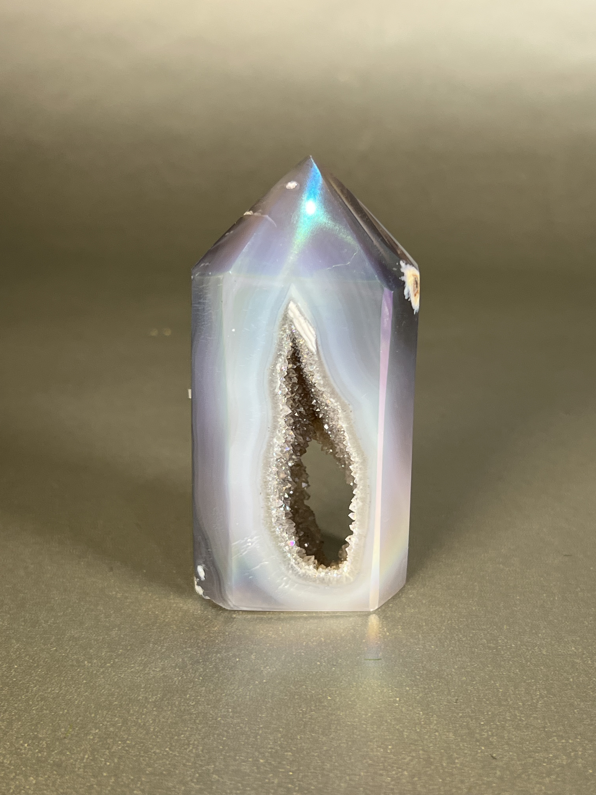 Experience the dreamy elegance of our Aura Agate Obelisk. Each one is uniquely crafted to exude a sense of luxury and exclusivity. Featuring the rare Aura Agate stone, this obelisk brings a touch of sophistication and beauty to any space. Elevate your decor with this truly one-of-a-kind piece. Approx. 2" x 3.5" Aura Agate Tower