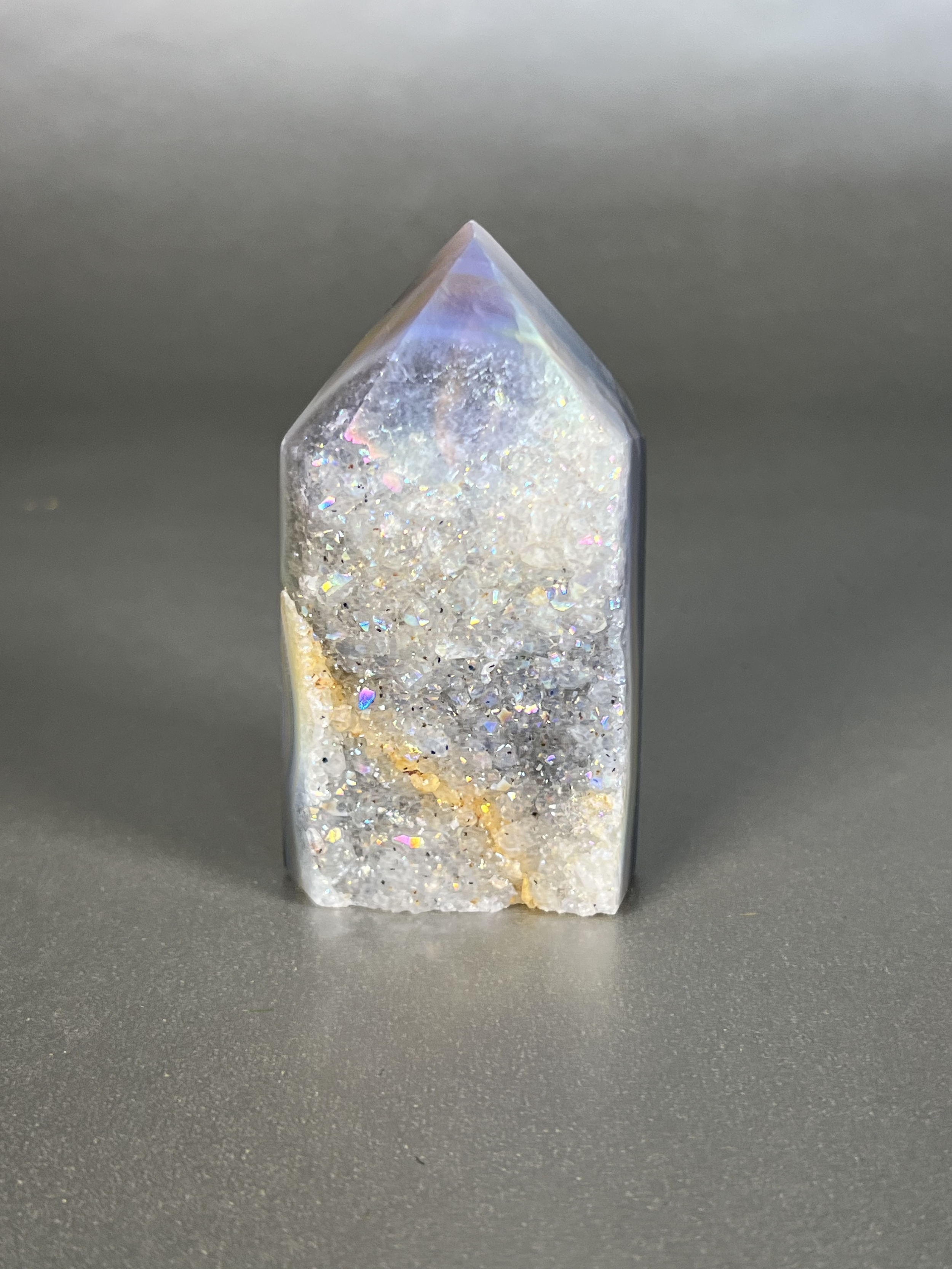 Experience the dreamy elegance of our Aura Agate Obelisk. Each one is uniquely crafted to exude a sense of luxury and exclusivity. Featuring the rare Aura Agate stone, this obelisk brings a touch of sophistication and beauty to any space. Elevate your decor with this truly one-of-a-kind piece. Approx. 2" x 3.5" Aura Agate Tower