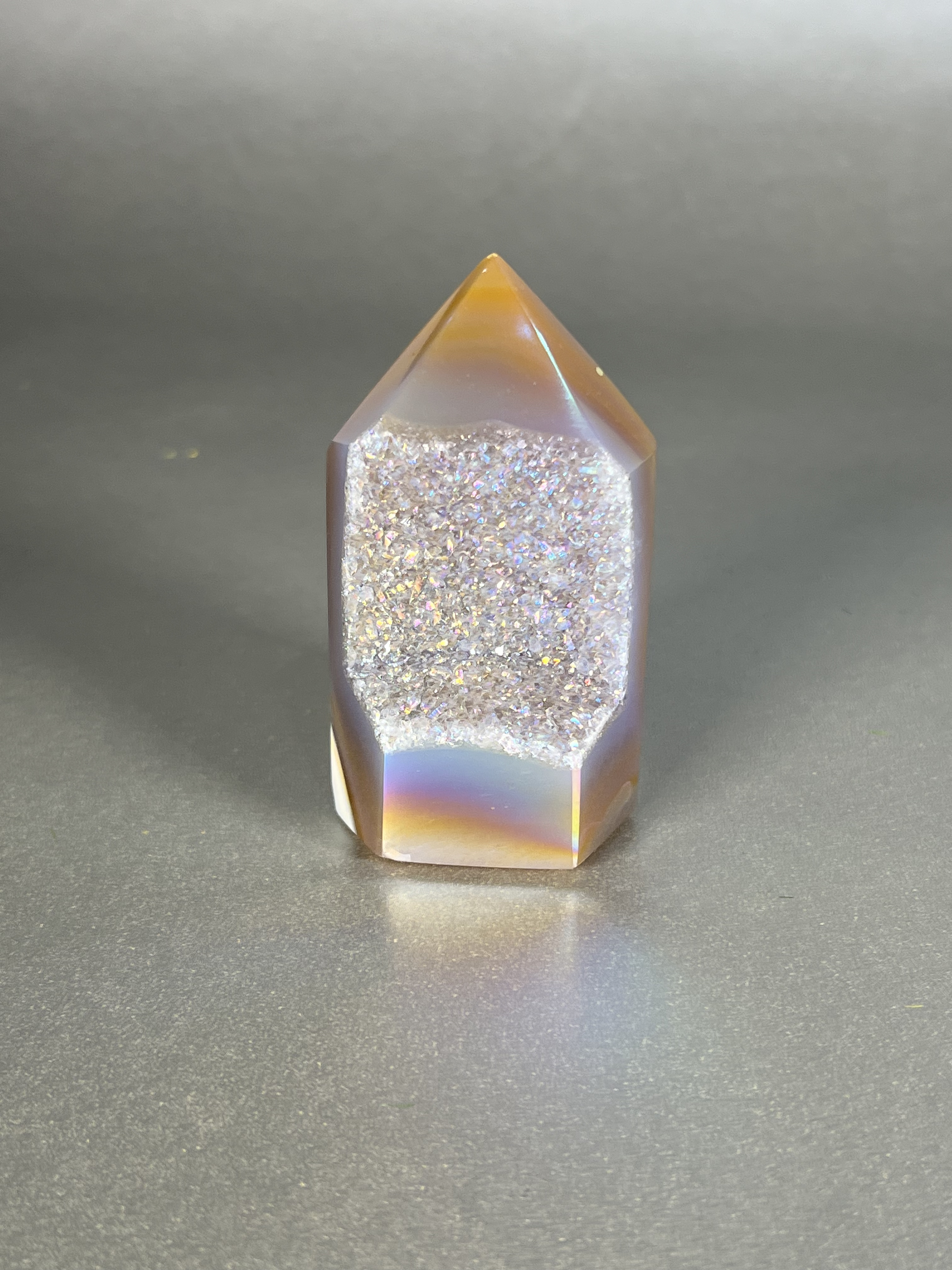 Experience the dreamy elegance of our Aura Agate Obelisk. Each one is uniquely crafted to exude a sense of luxury and exclusivity. Featuring the rare Aura Agate stone, this obelisk brings a touch of sophistication and beauty to any space. Elevate your decor with this truly one-of-a-kind piece. Approx. 1.5 "x 3" Aura Agate Tower