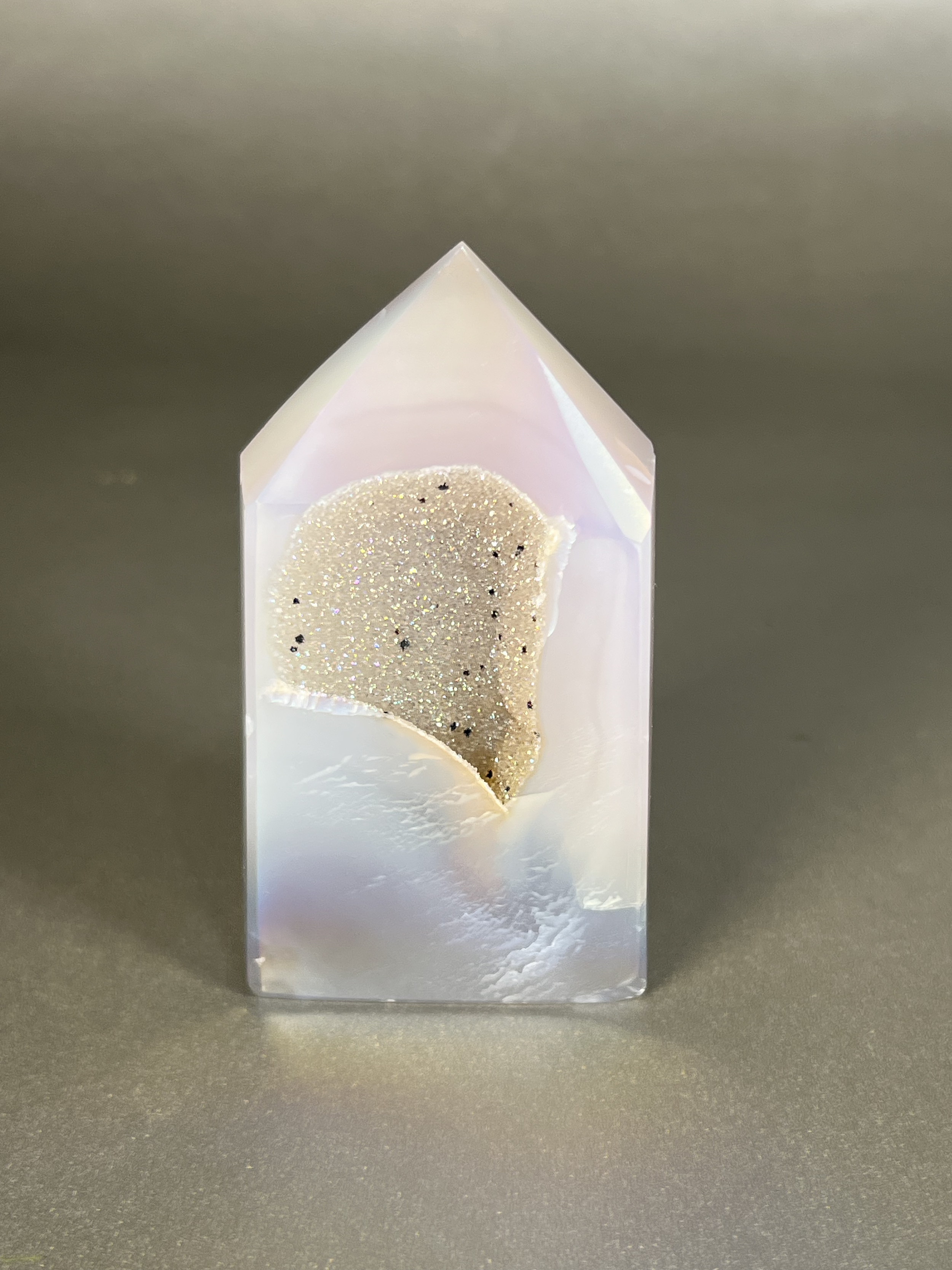 Experience the dreamy elegance of our Aura Agate Obelisk. Each one is uniquely crafted to exude a sense of luxury and exclusivity. Featuring the rare Aura Agate stone, this obelisk brings a touch of sophistication and beauty to any space. Elevate your decor with this truly one-of-a-kind piece. Approx. 2" x 3.5" Aura Agate Tower