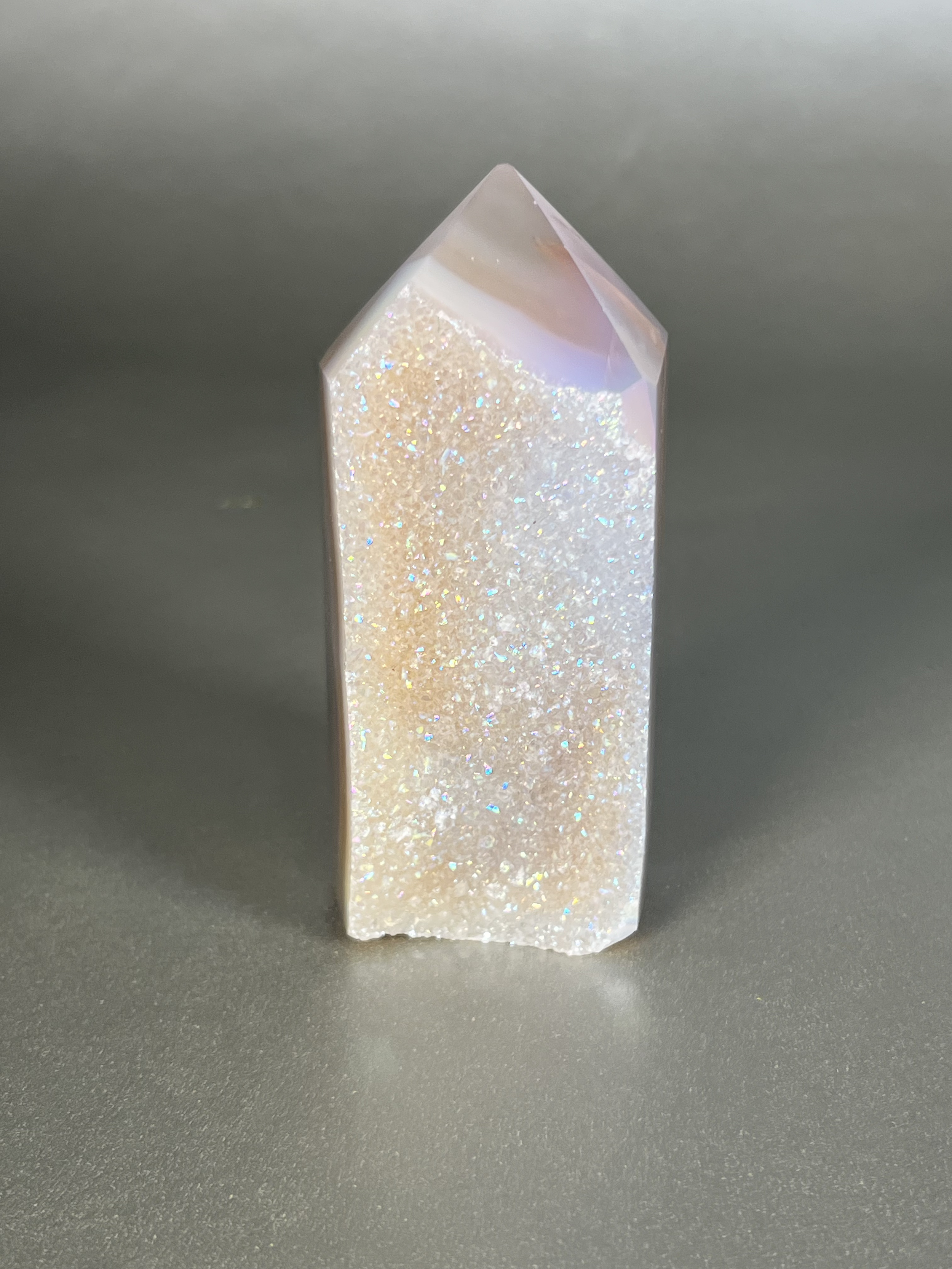 Experience the dreamy elegance of our Aura Agate Obelisk. Each one is uniquely crafted to exude a sense of luxury and exclusivity. Featuring the rare Aura Agate stone, this obelisk brings a touch of sophistication and beauty to any space. Elevate your decor with this truly one-of-a-kind piece. Approx. 1.5" x 4" Aura Agate Tower