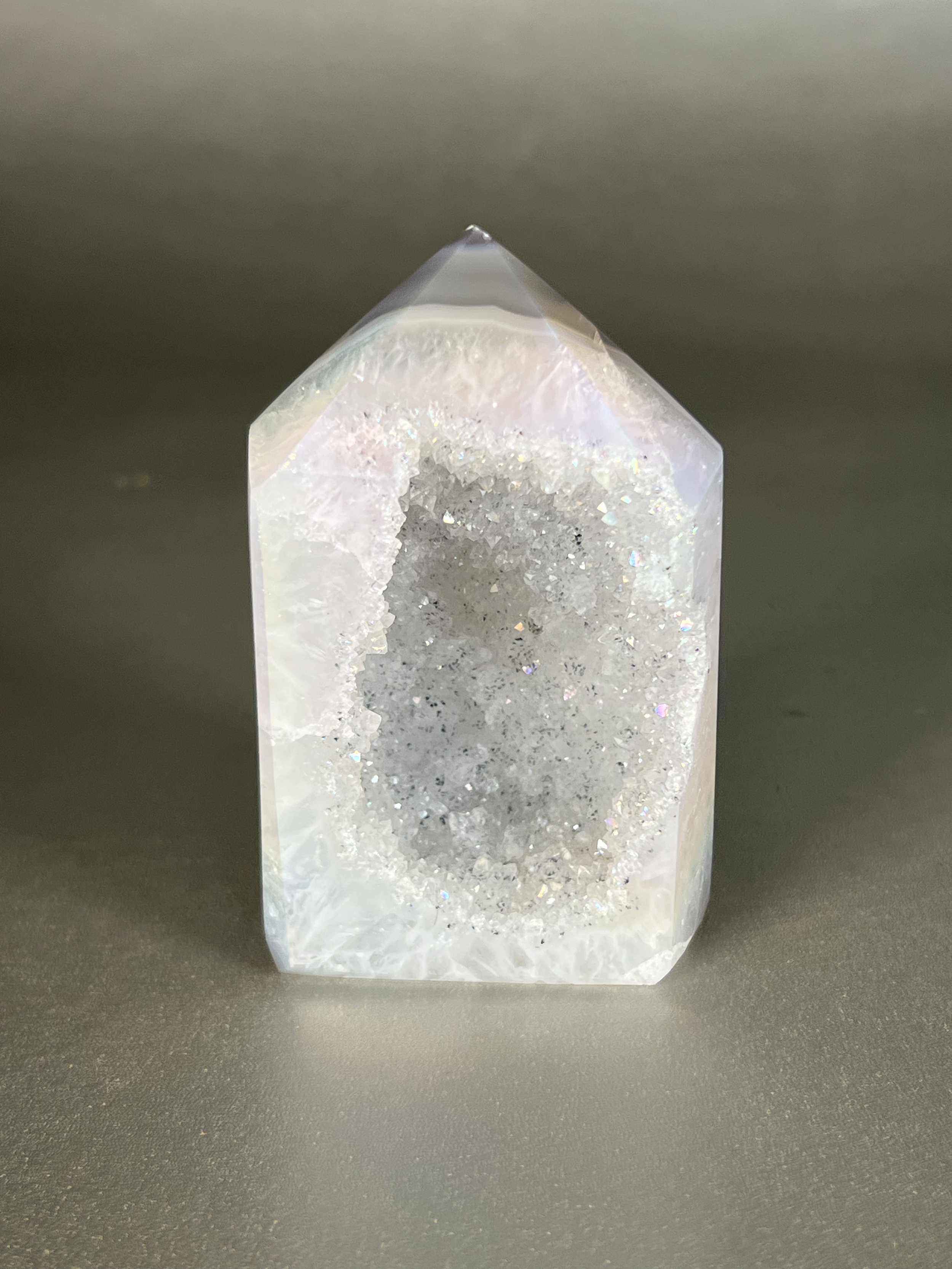 Experience the dreamy elegance of our Aura Agate Obelisk. Each one is uniquely crafted to exude a sense of luxury and exclusivity. Featuring the rare Aura Agate stone, this obelisk brings a touch of sophistication and beauty to any space. Elevate your decor with this truly one-of-a-kind piece. Approx. 2" x 3.5" Aura Agate Tower