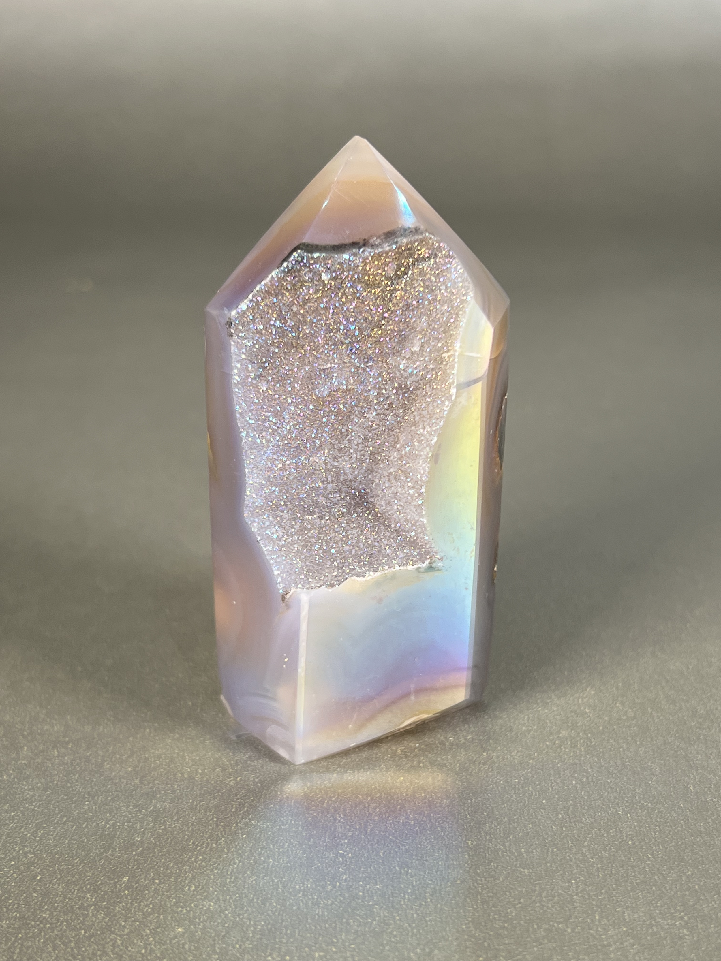 Experience the dreamy elegance of our Aura Agate Obelisk. Each one is uniquely crafted to exude a sense of luxury and exclusivity. Featuring the rare Aura Agate stone, this obelisk brings a touch of sophistication and beauty to any space. Elevate your decor with this truly one-of-a-kind piece. Approx. 1.5" x 3.5" Aura Agate Tower