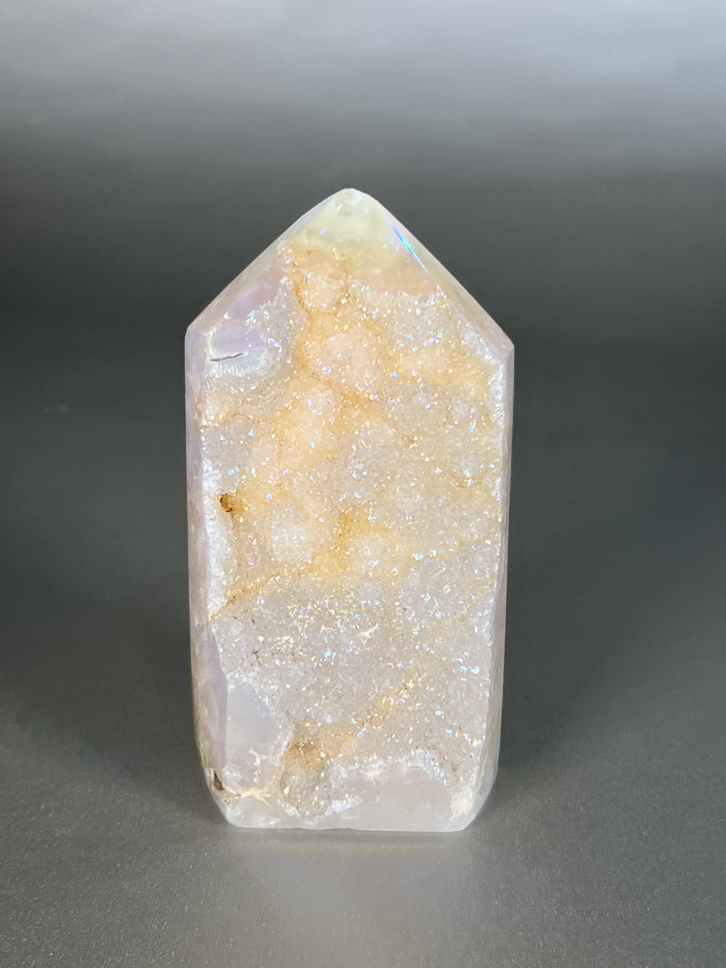 Experience the dreamy elegance of our Aura Agate Obelisk. Each one is uniquely crafted to exude a sense of luxury and exclusivity. Featuring the rare Aura Agate stone, this obelisk brings a touch of sophistication and beauty to any space. Elevate your decor with this truly one-of-a-kind piece. Approx. 2.5" x 4.5" Aura Agate Tower