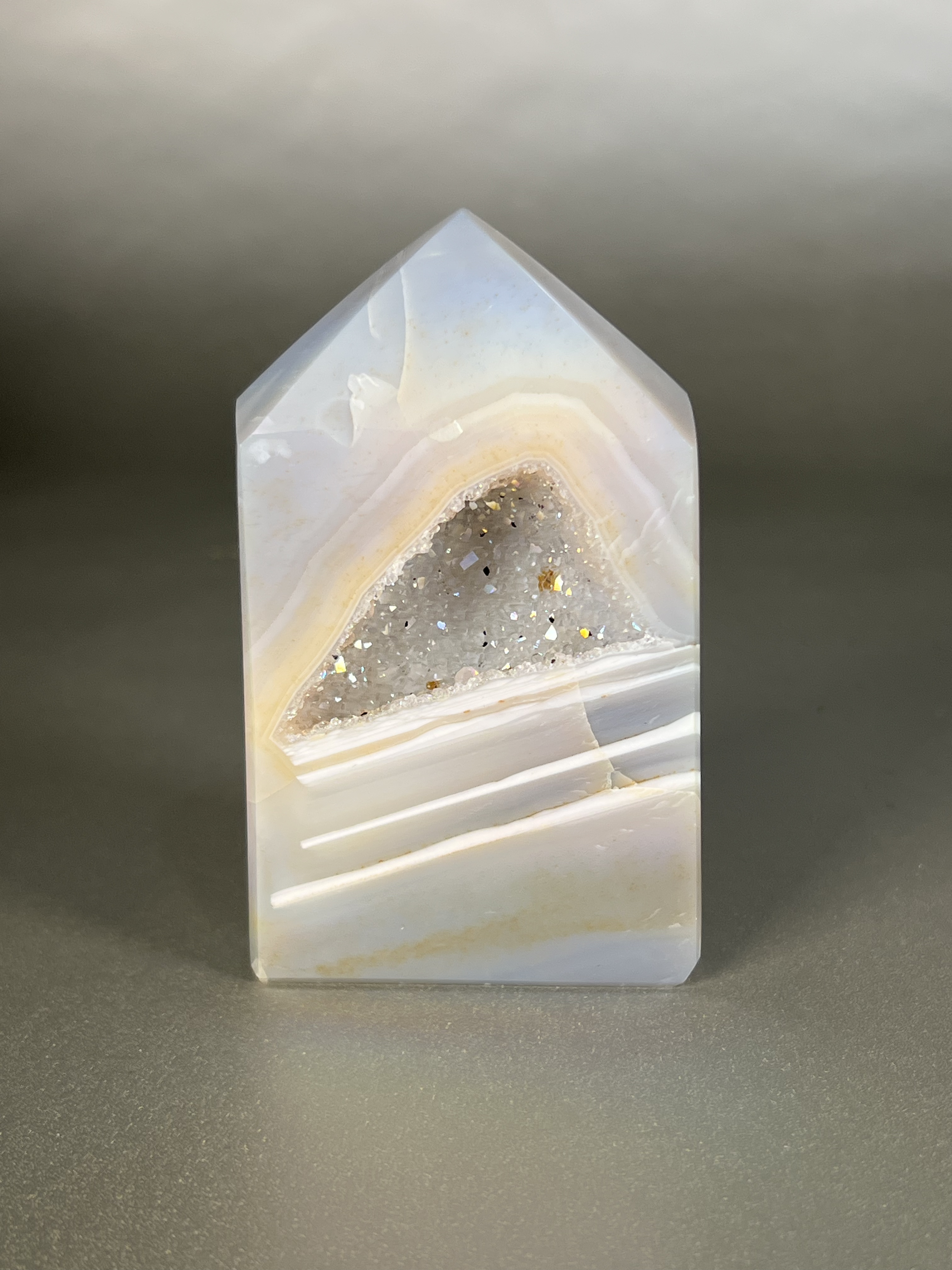 Experience the dreamy elegance of our Aura Agate Obelisk. Each one is uniquely crafted to exude a sense of luxury and exclusivity. Featuring the rare Aura Agate stone, this obelisk brings a touch of sophistication and beauty to any space. Elevate your decor with this truly one-of-a-kind piece. Approx. 2" x 4" Aura Agate Tower