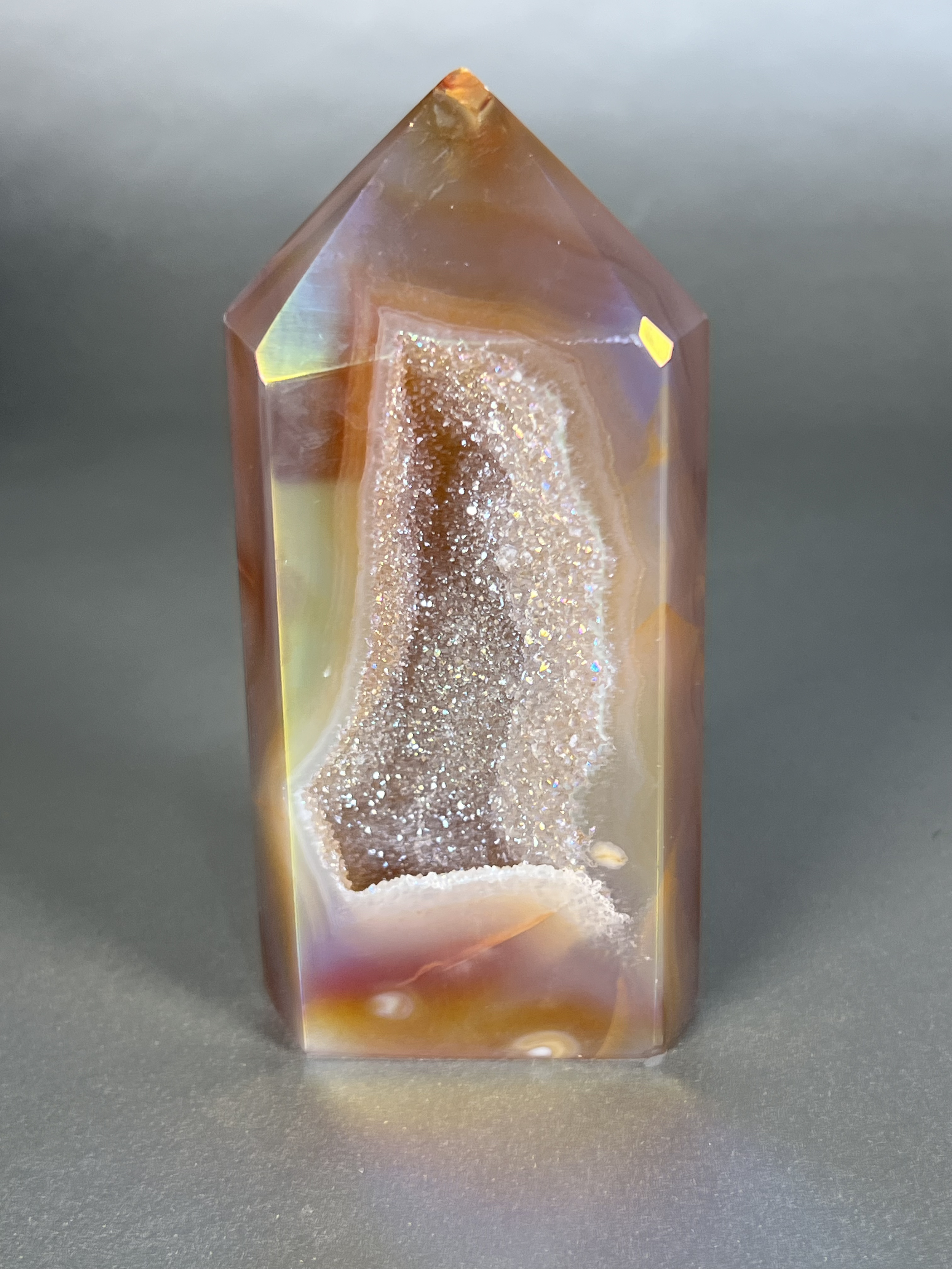 Experience the dreamy elegance of our Aura Agate Obelisk. Each one is uniquely crafted to exude a sense of luxury and exclusivity. Featuring the rare Aura Agate stone, this obelisk brings a touch of sophistication and beauty to any space. Elevate your decor with this truly one-of-a-kind piece. Approx. 2" x 5" Aura Agate Tower