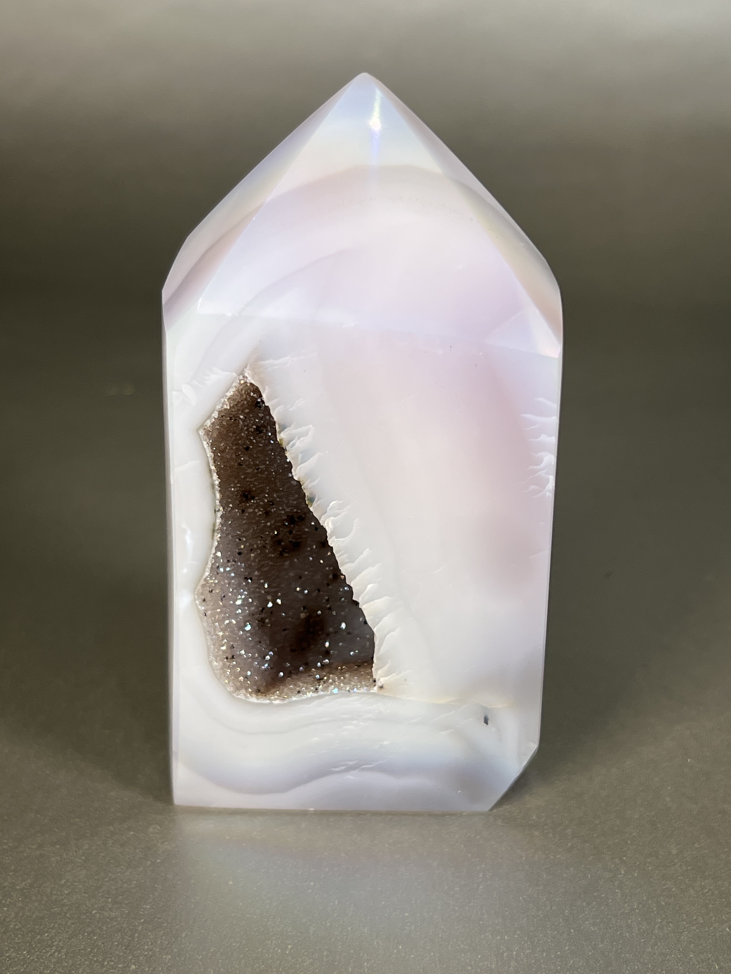 Experience the dreamy elegance of our Aura Agate Obelisk. Each one is uniquely crafted to exude a sense of luxury and exclusivity. Featuring the rare Aura Agate stone, this obelisk brings a touch of sophistication and beauty to any space. Elevate your decor with this truly one-of-a-kind piece. Approx. 2.5" x 4.5" Aura Agate Tower