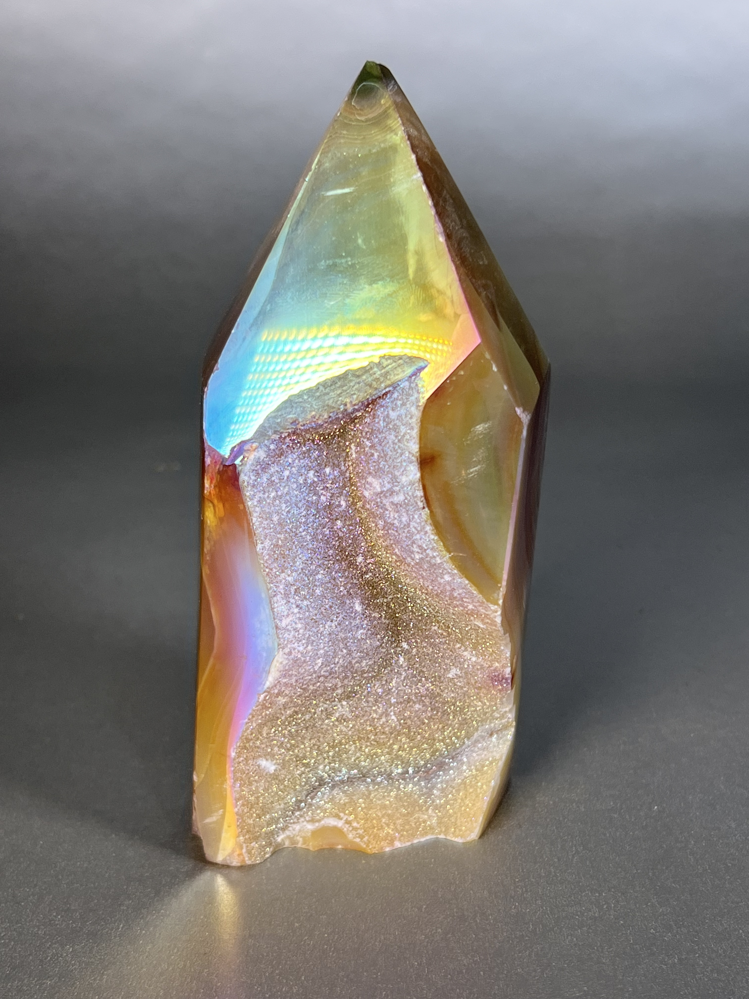 Experience the dreamy elegance of our Aura Agate Obelisk. Each one is uniquely crafted to exude a sense of luxury and exclusivity. Featuring the rare Aura Agate stone, this obelisk brings a touch of sophistication and beauty to any space. Elevate your decor with this truly one-of-a-kind piece. Approx. 2.5"x5.5" Aura Agate Tower