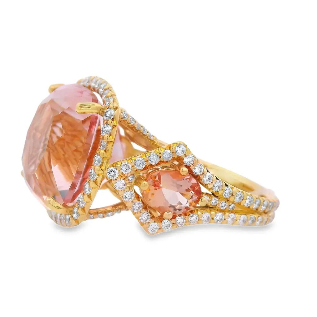 Radiating warmth and elegance, this 18k yellow gold ring features a stunning 13.25-carat morganite at its center. Accented by 1.22 carats of peach topaz and 1.56 carats of sparkling diamonds, it’s a beautifully balanced design that captures light—and attention—with every angle.-18k Yellow gold-Morganite, 13.25ct-Peach topaz, 1.22cts-Diamonds, F-G/ VS 1.56ctsItem# 200-2000148 Sunset Glow Ring