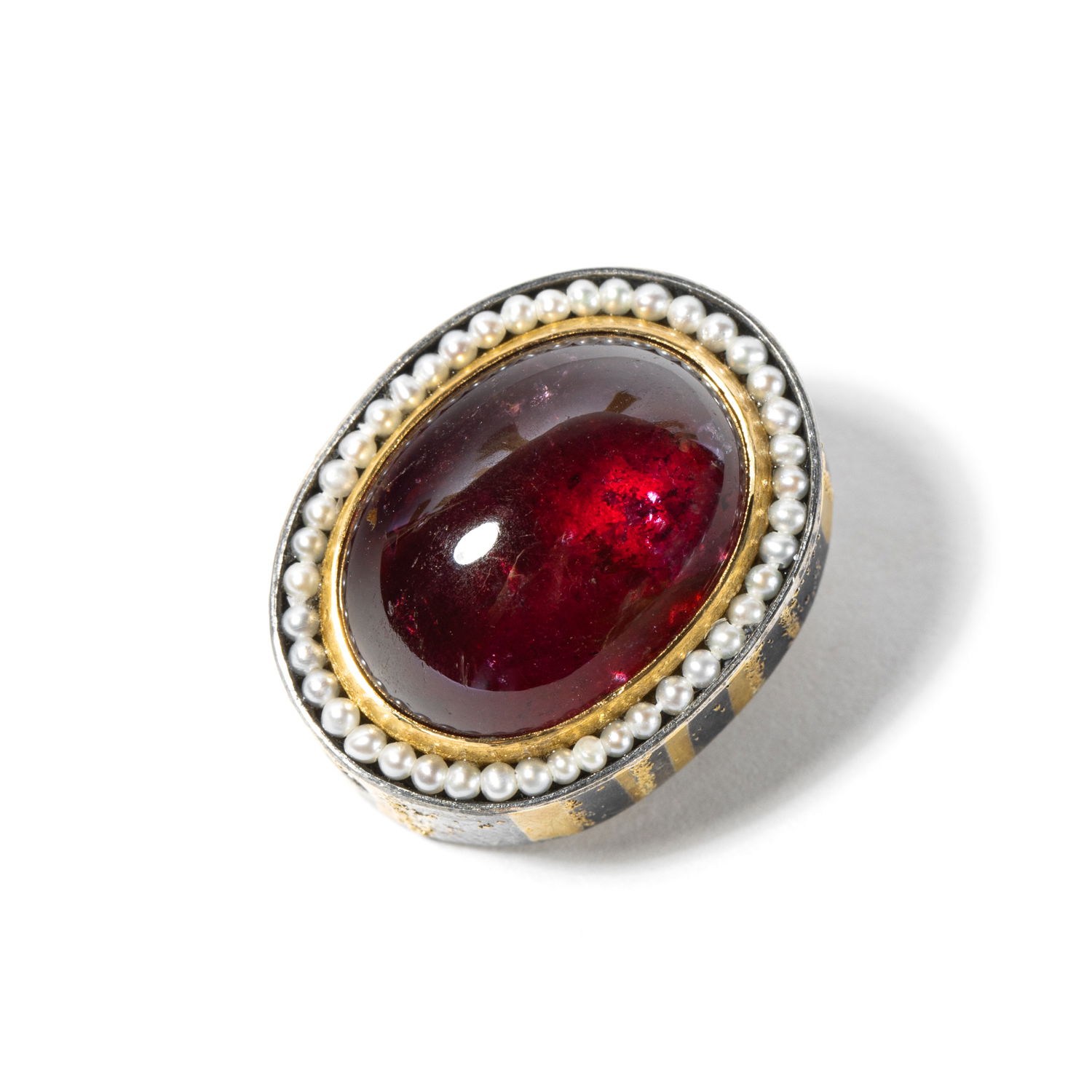 A sterling silver pendant that features a cabochon tourmaline in a glowing frame of 24k yellow gold and delicate seed pearls. It's rich and bold yet refined; a modern heirloom that bridges past and present with effortless grace. -Sterling silver & 24k yellow gold-Tourmaline, 19.25cts-Round diamonds, 0.06cts-Seed pearlsItem# 806-2000194 Tourmaline Pendant