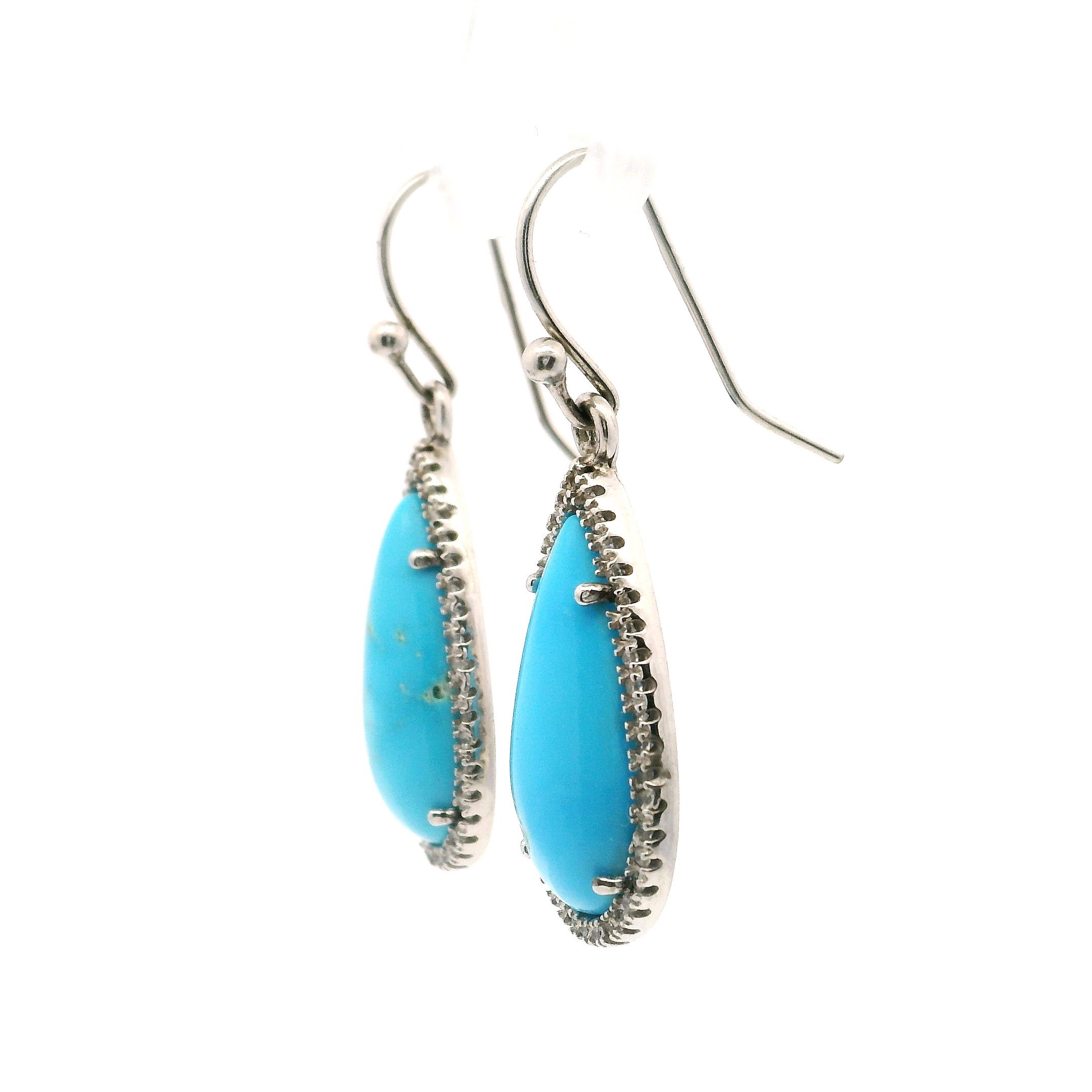 Elevate your style with these exquisite Sleeping Beauty Turquoise Earrings, delicately handcrafted in 925 sterling silver. Each dangle earring features a vibrant Sleeping Beauty turquoise gemstone, celebrated for its captivating sky-blue hue. Surrounding the turquoise, brilliant cubic zirconia stones are set in a sleek bezel, adding a touch of sparkle and elegance. The earrings are lightweight and comfortable for all-day wear, making them perfect for any occasion—from casual outings to sophisticated soirées. Sleeping Beauty Turquoise Earrings with CZ set Bezel