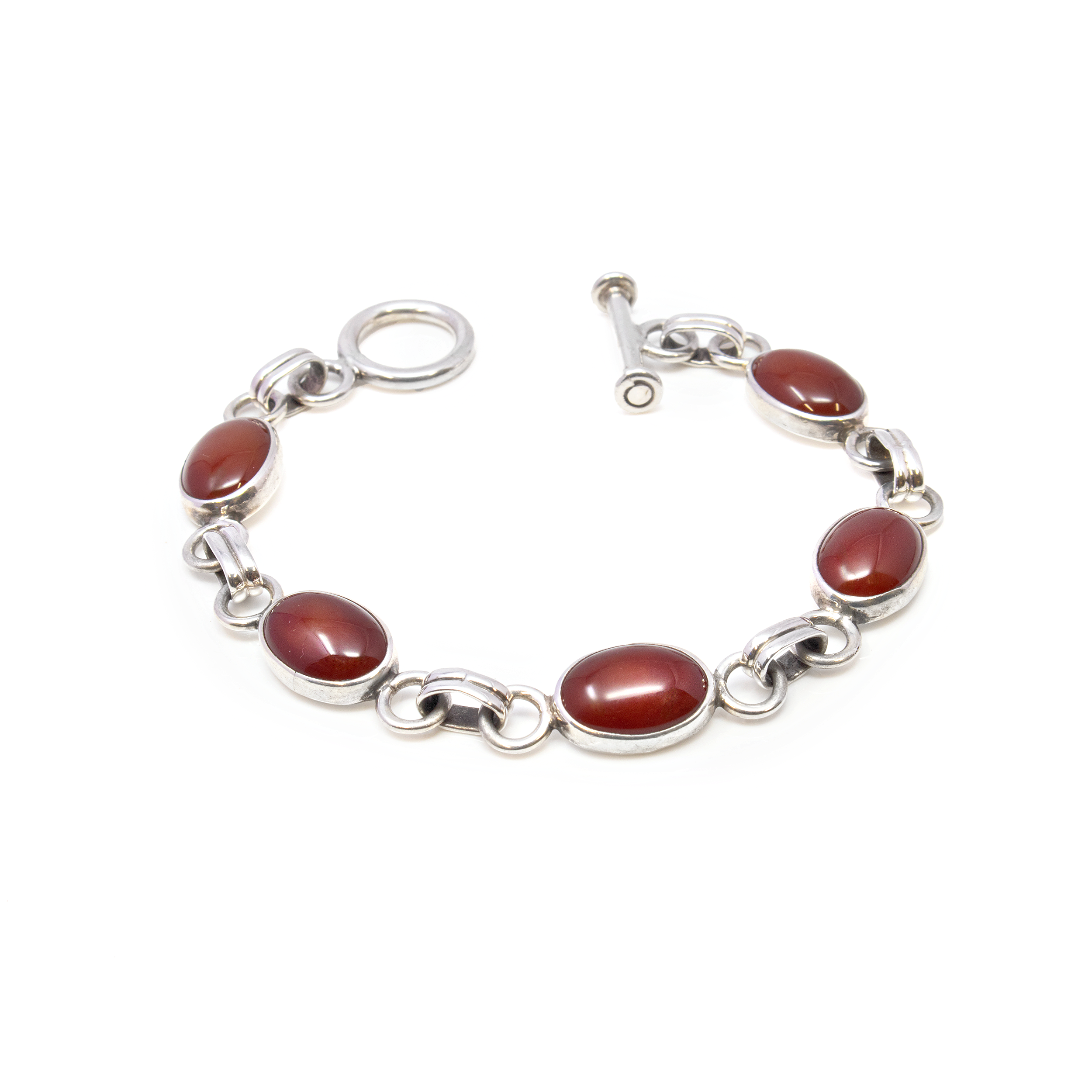 Elegance meets vibrant energy with our Carnelian Bracelet, featuring five stunning oval gemstones meticulously set with sterling silver spacer links. This exquisite piece is more than just jewelry; it's a celebration of natural beauty and craftsmanship. Each bracelet showcases five hand-selected Carnelian stones, renowned for their rich, fiery hues that range from deep reds to warm oranges. These gemstones are not only beautiful but also believed to possess energizing and stabilizing properties, making this bracelet an ideal choice for those seeking both style and spiritual balance. Carnelian Bracelet 5 Ovals With Spacer Links & Toggle