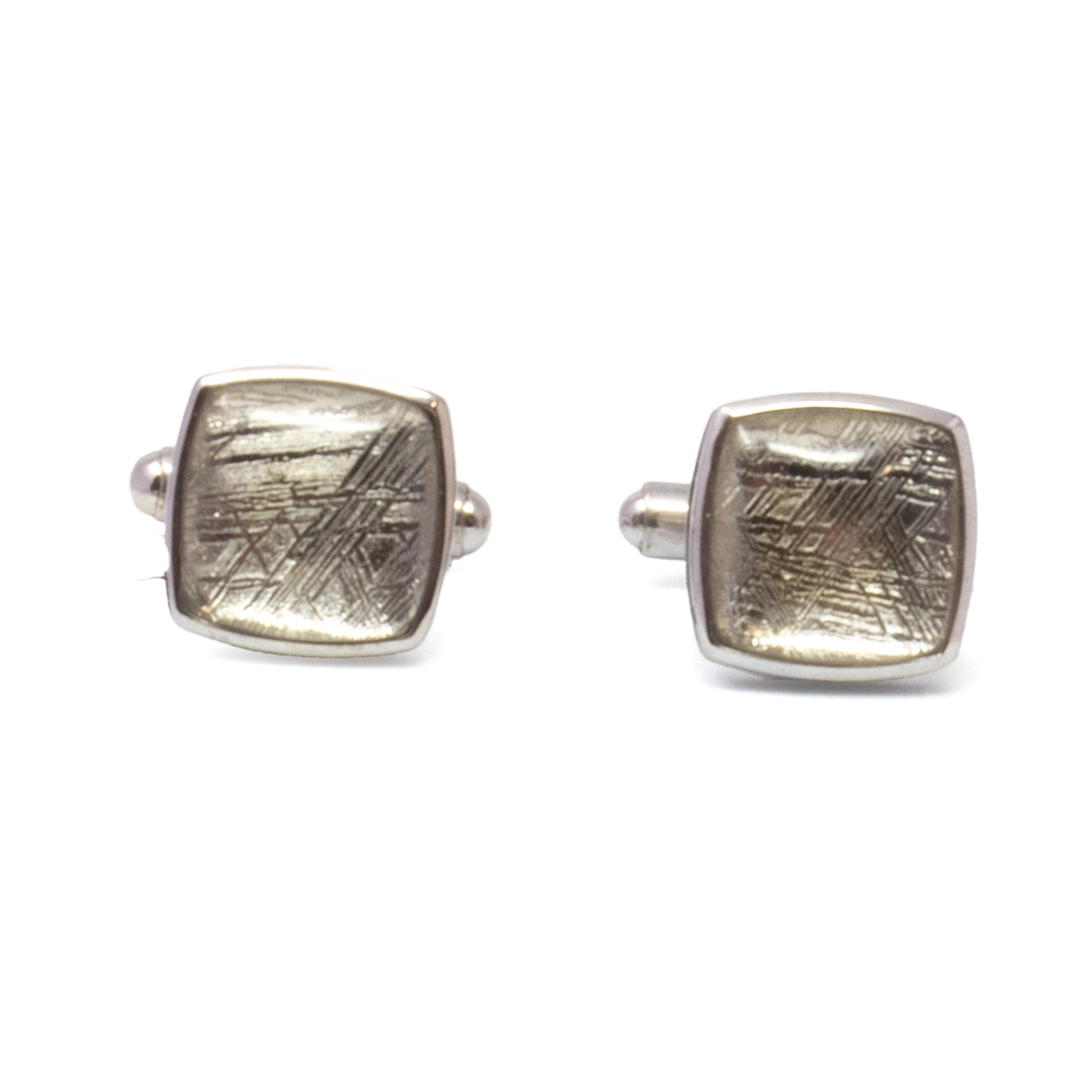 Elevate your formal ensemble with these extraordinary Muonionalusta Meteorite Cufflinks, showcasing genuine meteorite slices over 4 billion years old. Each cambered square reveals the distinct Widmanstätten pattern—etched by nature and impossible to replicate—set in a polished 925 sterling silver bezel with detailed side beading for added refinement. A seamless fusion of celestial history and artisan craftsmanship, these cufflinks are more than accessories—they’re wearable cosmic relics. Ideal for collectors, connoisseurs, or as a truly unforgettable gift. Muonionalusta Meteorite Cufflinks - Cambered Square On Silver Bezel With Beading On Sides