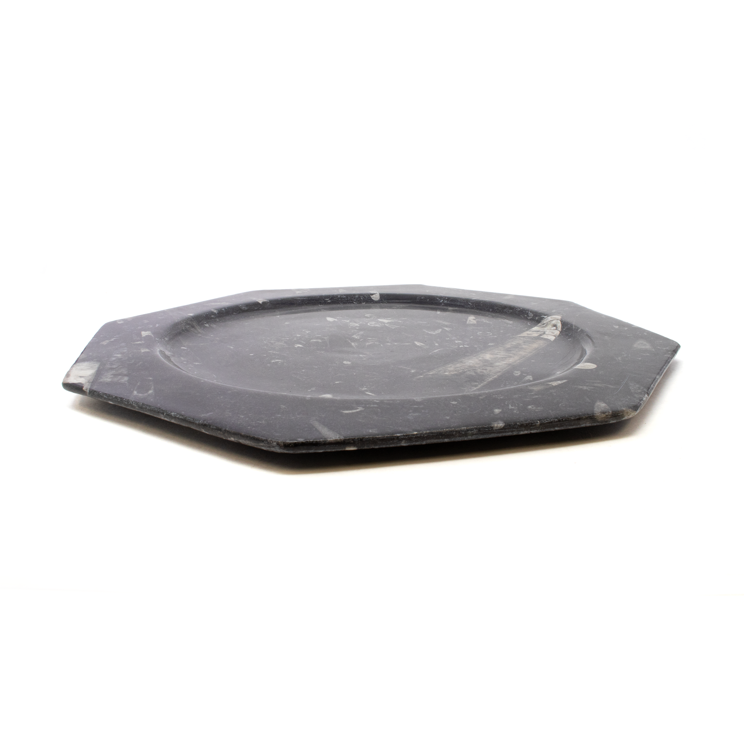 Elevate your dining experience with the stunning Orthoceras Seabed Octagonal Charger Plate, a true masterpiece from Rare Earth Gallery's exclusive collection of home accessories and tableware. This remarkable charger plate seamlessly blends prehistoric elegance with contemporary design, making it a captivating addition to any table setting. Each charger plate is meticulously crafted using genuine Orthoceras fossils, remnants of an ancient marine creature that roamed the seas over 400 million years ago. The distinctive, elongated shells of these fossils create a mesmerizing, one-of-a-kind pattern, ensuring that no two plates are alike. Orthoceras Seabed Octagonal Charger Plate