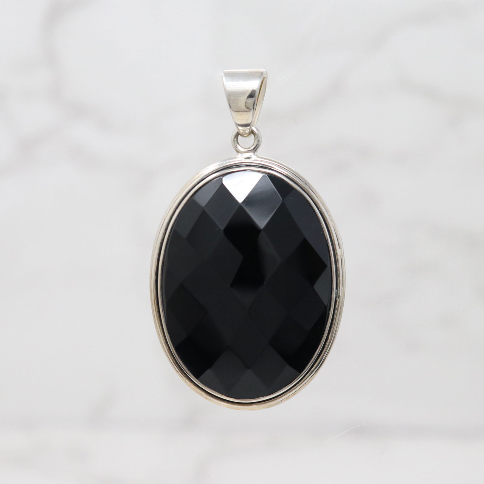 Elevate your style with our Onyx gemstone pendant. Its oval shape highlights the depth and shimmer of the Onyx, giving it a mesmerizing glow that enhances any look. Meticulously crafted to reflect light beautifully, this pendant exudes luxury and elegance. Perfect for any occasion. Black Onyx Faceted Oval Pendant