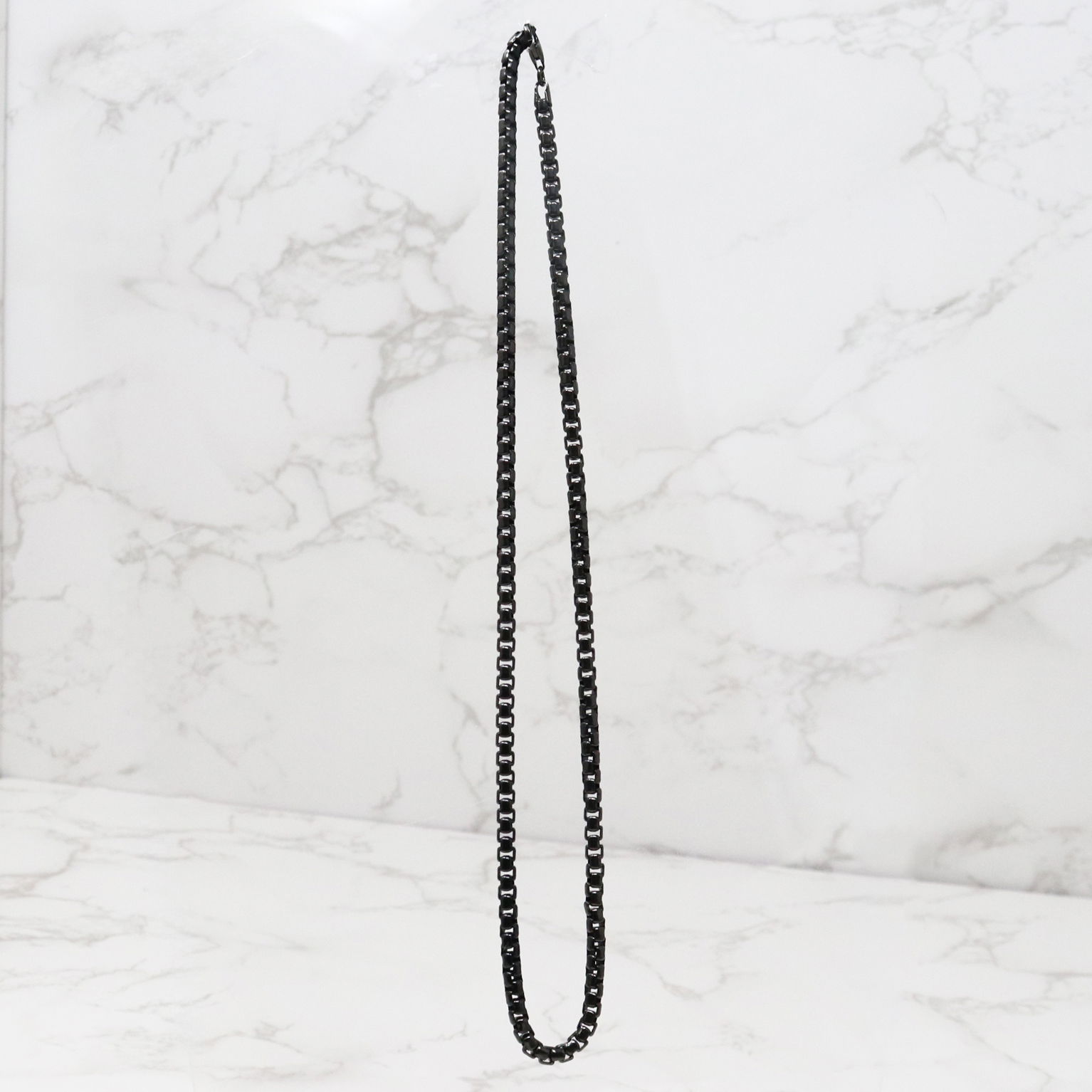 This stylish chain features a long-lasting Ruthenium coating that enhances its visual appeal. The 18-inch length offers both comfort and visibility, secured with a reliable clasp. Its durability ensures that it will last you for years to come, while also providing a sleek and stylish look. The dark-gray hue puts it in the platinum family of metals. This chain is perfect for anyone looking for a durable, stylish piece that will elevate any outfit. 18" Ruthenium Round Box Chain