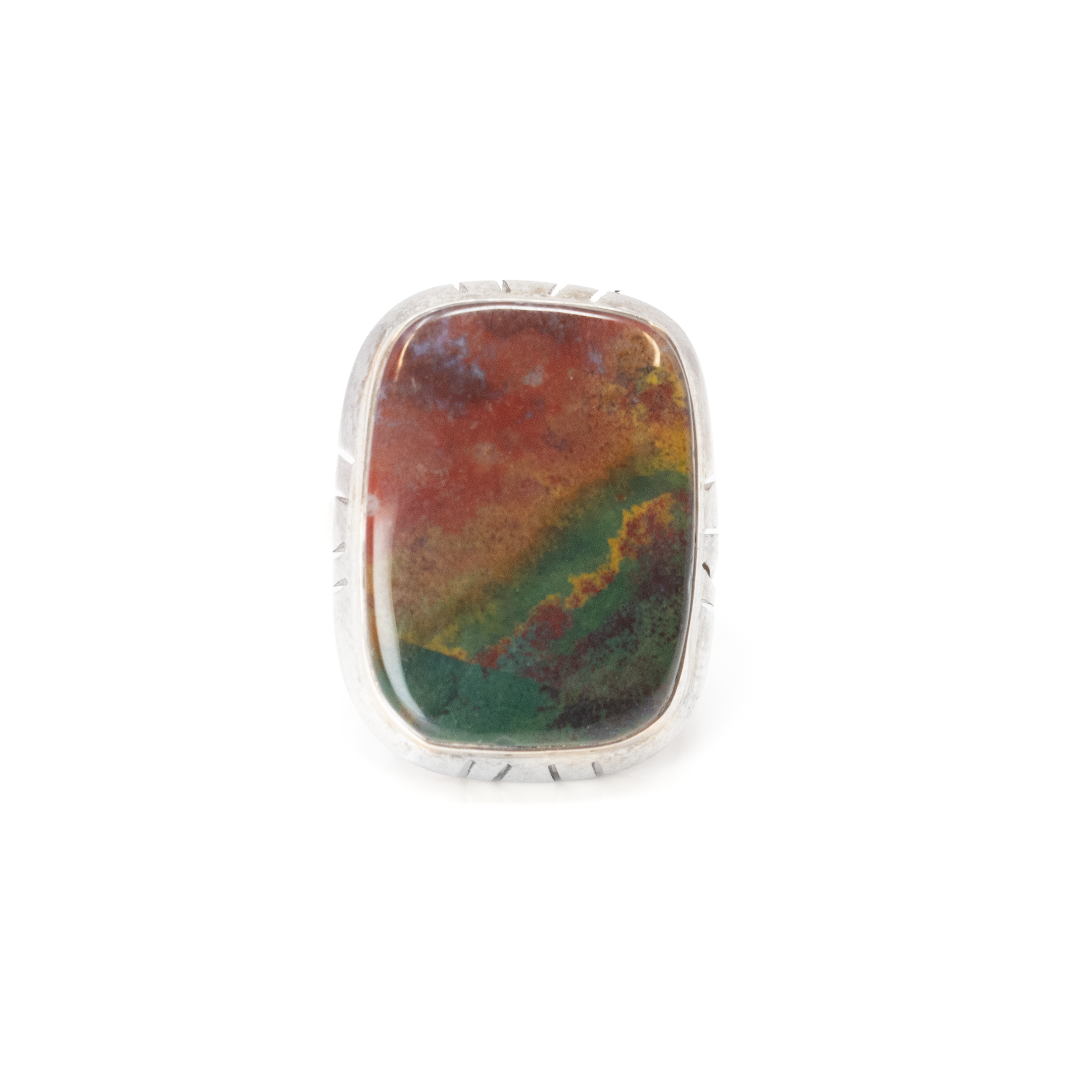 Introducing the exquisite Bloodstone Ring, a captivating piece of jewelry that effortlessly blends elegance with a touch of mystique. This stunning ring showcases a rectangle cabochon bloodstone with beautifully rounded edges, exuding a sense of timeless sophistication. Each stone is uniquely marbled with deep greens and intriguing red flecks, believed to hold healing properties and symbolize strength and courage.Encasing this magnificent gemstone is a meticulously crafted line-stamped silver step bezel. Made from lustrous 925 sterling silver, the bezel not only secures the bloodstone in place but also adds an extra layer of dimension and style. The detailed line stamping creates a subtle yet distinctive texture, highlighting the natural beauty of the gemstone. Bloodstone Ring - Rectangle Cabochon With Rounded Edges & Line Stamped Silver Step Bezel Sz5.5