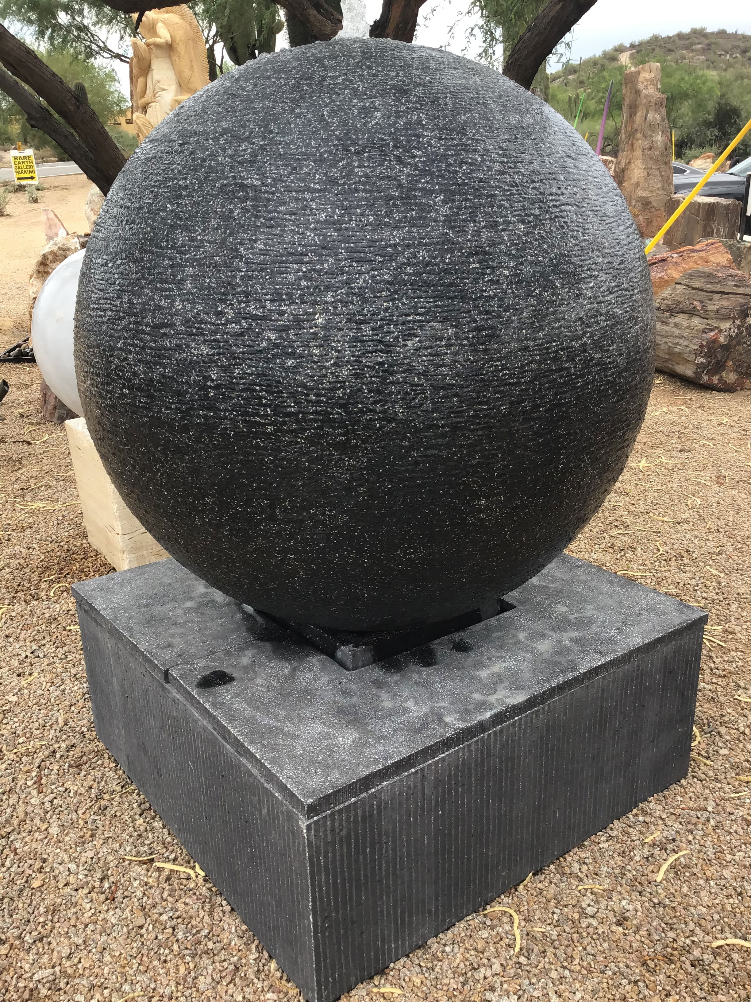 Create a serene and visually appealing outdoor space with this black cast concrete sphere fountain. Its large size and tranquil water feature will bring a sense of peace and enhance the beauty of your yard, garden, or patio. Let Rare Earth Gallery’s white-glove service make your fountain dreams come true—simply choose your fountain, tell us where it goes, and we’ll handle the rest, from delivery to installation. IMPORTANT: the purchase price listed is for the FOUNTAIN ONLY and DOES NOT INCLUDE the cost of a pump, parts or installation. Before purchasing a fountain online, we STRONGLY recommend you call us at (480) 575-4360 for a FREE consultation to discuss these additional costs and schedule a pre-site inspection. Also, free shipping does NOT apply to fountains, please call for a quote. 44" Diameter Black Cast Concrete Sphere Fountain - Large