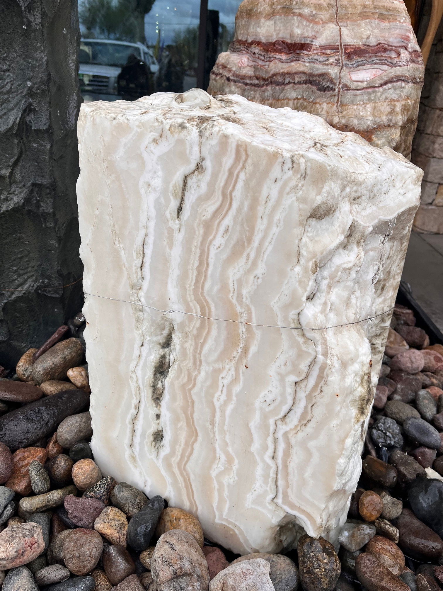 The Nube Onyx Block Fountain enhances the serenity and visual appeal of your yard, garden, or patio. With three sides cut, it creates an aura of tranquility and adds a touch of elegance to your outdoor space. Let Rare Earth Gallery’s white-glove service make your fountain dreams come true—simply choose your fountain, tell us where it goes, and we’ll handle the rest, from delivery to installation. IMPORTANT: the purchase price listed is for the FOUNTAIN ONLY and DOES NOT INCLUDE the cost of a basin, pump, parts or installation. Before purchasing a fountain online, we STRONGLY recommend you call us at (480) 575-4360 for a FREE consultation to discuss these additional costs and schedule a pre-site inspection. Also, free shipping does NOT apply to fountains, please call for a quote. Nube Onyx Block Fountain With 3 Sides Cut