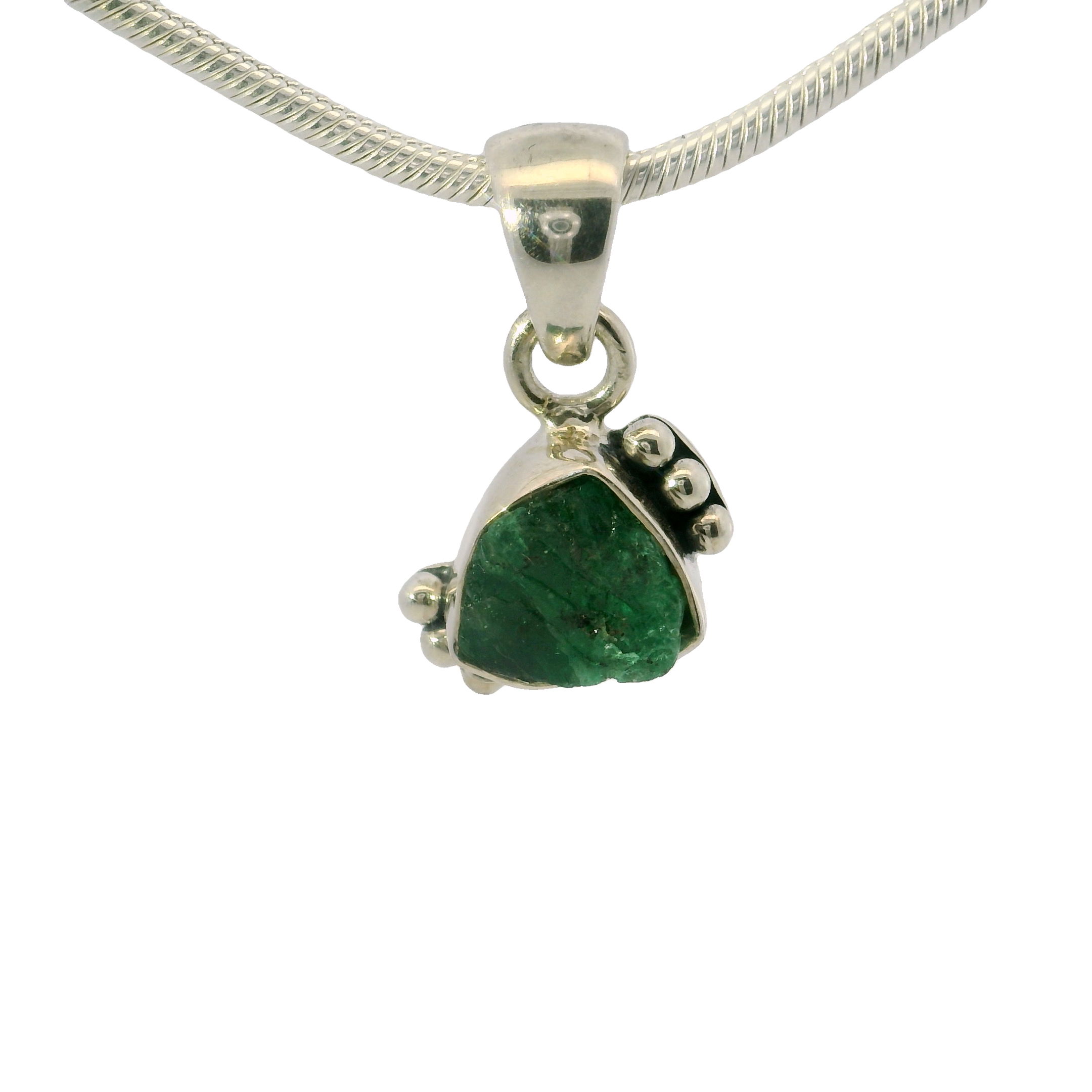 Elevate your jewelry collection with our stunning Emerald Pendant, a true statement piece that exudes natural beauty and timeless elegance. This unique pendant features a rough freeform emerald, celebrated for its vibrant green hue and distinct inclusions that give each piece a one-of-a-kind character.Meticulously handcrafted, the emerald is set in a durable 925 sterling silver bezel that elegantly frames the gemstone. Skilled artisans have adorned the side with delicate silver beading, adding a touch of sophistication and enhancing the pendant's overall allure.The freeform cut of the emerald highlights its organic shape and raw beauty, making it an embodiment of nature's artistry. Each emerald is carefully chosen for its rich color and natural imperfections, ensuring that your pendant is uniquely yours. Emerald Pendant - Rough Freeform With 925 Sterling Silver Bezel & Beading On Side