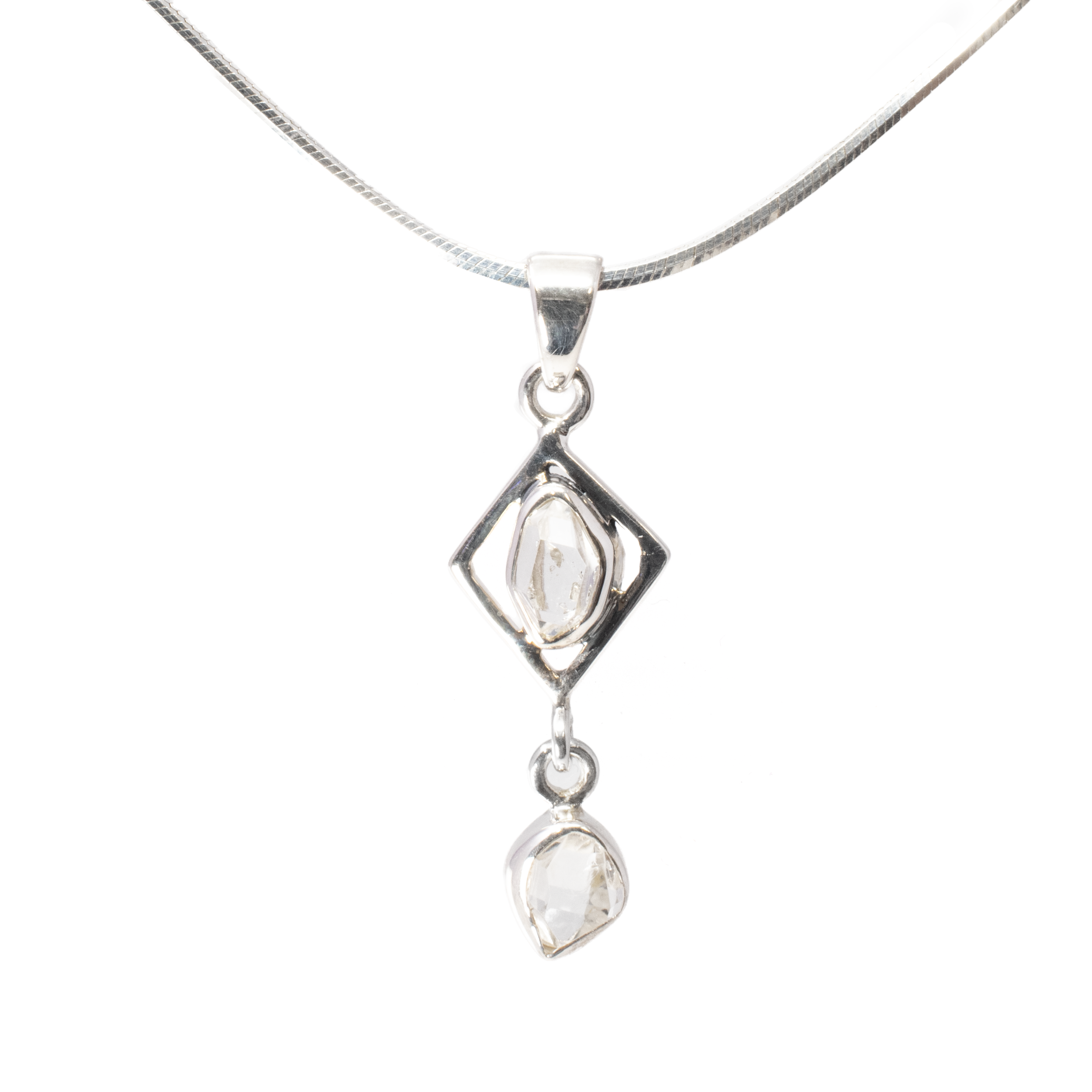 Introducing our stunning Herkimer Diamond Pendant, a true masterpiece of nature's beauty and artisan craftsmanship. This exquisite piece features a faceted freeform Herkimer diamond, elegantly set within a rhombus-shaped frame of high-quality 925 sterling silver. The shimmering allure of the Herkimer diamond is further accentuated by a symmetrically arranged dangling faceted freeform, creating a harmonious balance of sparkle and sophistication. Each Herkimer diamond, known for its exceptional clarity and natural geometric forms, is ethically sourced and carefully selected for its unique characteristics, making every pendant truly one-of-a-kind. The rhombus setting, meticulously crafted from sterling silver, enhances the stone's brilliance while providing a contemporary touch to this timeless design. Herkimer Diamond Pendant - Faceted Freeform Set In 925 Sterling Silver Rhombus With Dangling Faceted Freeform Below