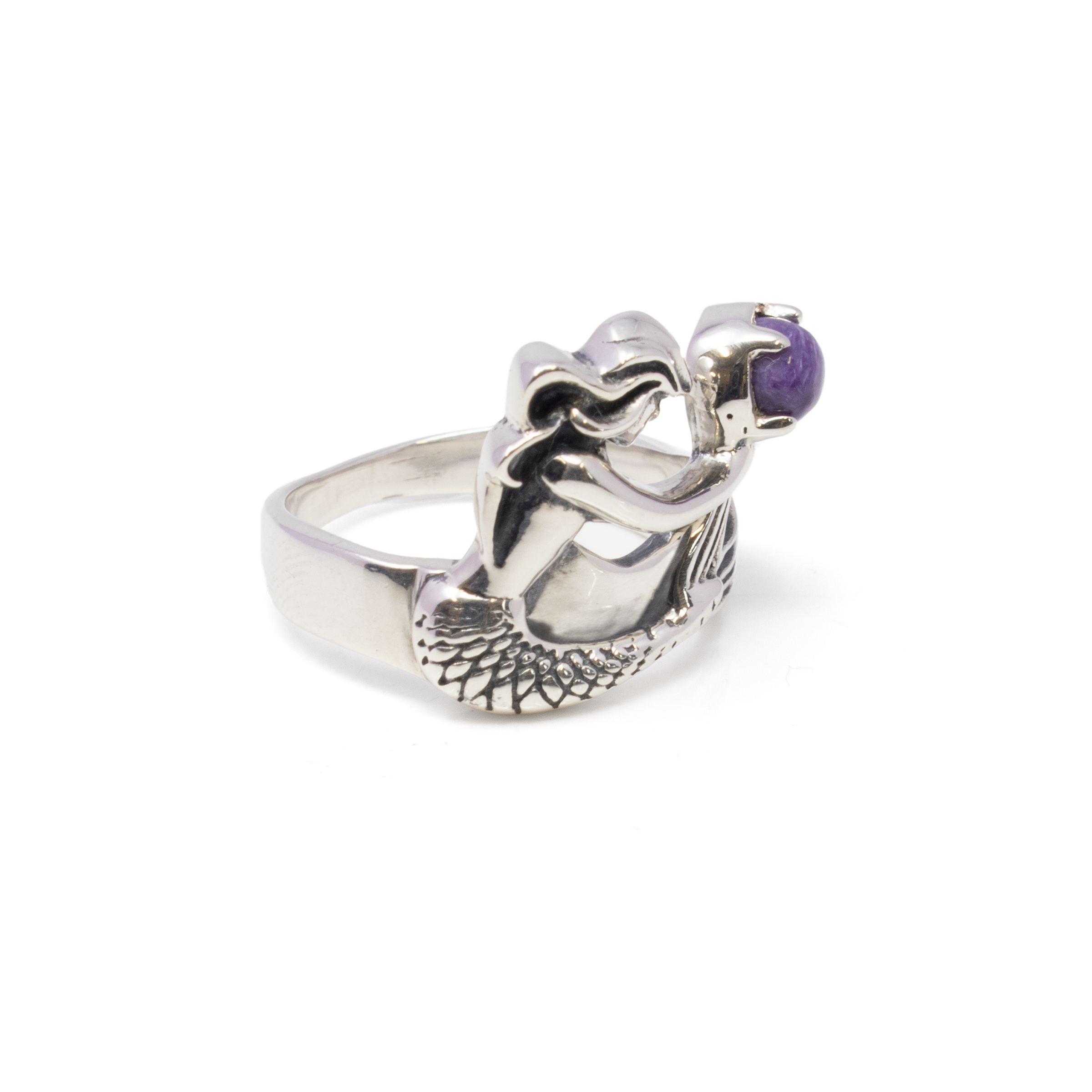 Dive into elegance with our exquisite Sugilite Ring, a harmonious blend of mystical charm and oceanic beauty. This stunning piece features a captivating round cabochon of mesmerizing Sugilite, renowned for its rich purple hues and soothing energy. Encasing this enchanting gemstone is a beautifully crafted 925 sterling silver setting, meticulously designed to resemble a mermaid, symbolizing grace and allure. The ornate details of the mermaid's tail and flowing hair accentuate the vibrancy of the Sugilite, creating a whimsical yet sophisticated look. Sugilite Ring - Round Cabochon Held By 925 Sterling Silver Ornate Mermaid Sz10