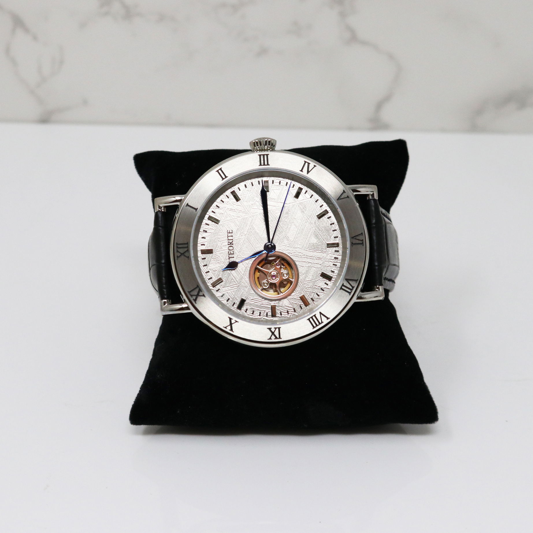 Introducing a unique timepiece with a captivating tale. Crafted with a meteorite dial that reveals stunning Widmanstätten lines, showcasing its crystalline structure. The elegant black leather band adds sophistication and durability. Perfect for both casual and formal wear, its adjustable clasp ensures a secure fit. Experience the beauty and versatility of this remarkable watch. Muonionalusta Meteorite Watch - Miyota Movement with Black leather Band & Cobalt Blue Hands - Roman Numeral Time Stamps