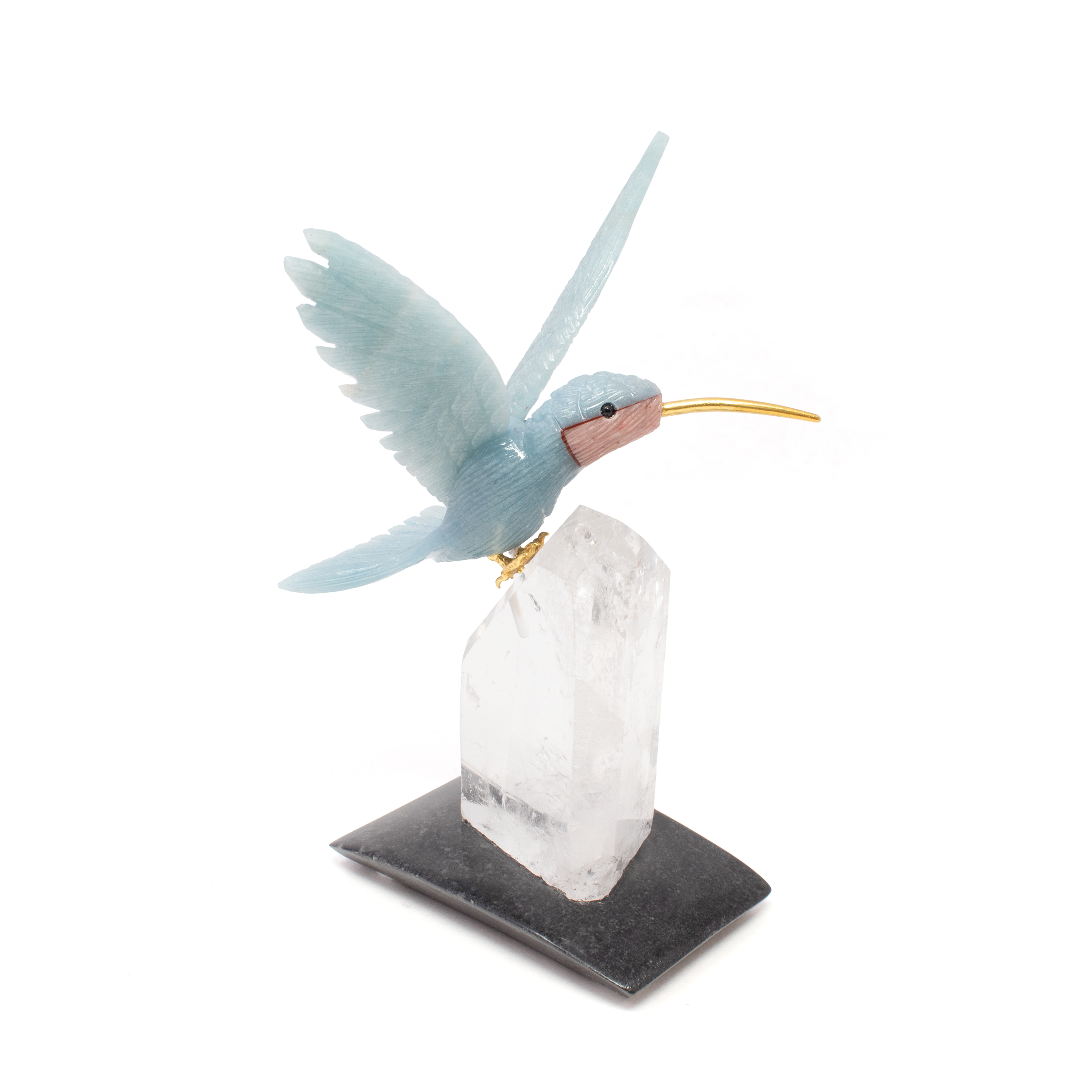 The Blue Calcite Hummingbird Carving Perched on Quartz Crystal Point is an exquisite piece of art that beautifully marries the natural splendor of minerals with expert craftsmanship. This captivating carving features a delicate hummingbird, meticulously sculpted from soothing blue calcite, known for its gentle color and calming energy. The hummingbird, a symbol of joy, adaptability, and resilience, is shown in a poised resting position, capturing the grace and elegance of these incredible creatures.Perched atop a stunning quartz crystal point, this sculpture creates a striking vertical display that enhances any space with its serene and uplifting presence. The clear quartz base not only provides a sturdy foundation but also amplifies the healing properties associated with both calcite and quartz, promoting clarity, positivity, and balance.Ideal for nature lovers, bird enthusiasts, and crystal collectors alike, this unique piece serves as a perfect decorative accent for home or office. Whether placed on a desk, shelf, or mantelpiece, the Blue Calcite Hummingbird Carving on Quartz Crystal Point brings a touch of nature’s beauty inside, inspiring a sense of tranquility and wonder. Embrace the elegance and symbolic meaning of this remarkable sculpture and let it elevate the ambiance of your surroundings. Blue Calcite Hummingbird Carving Perched on Quartz Crystal Point Vertical