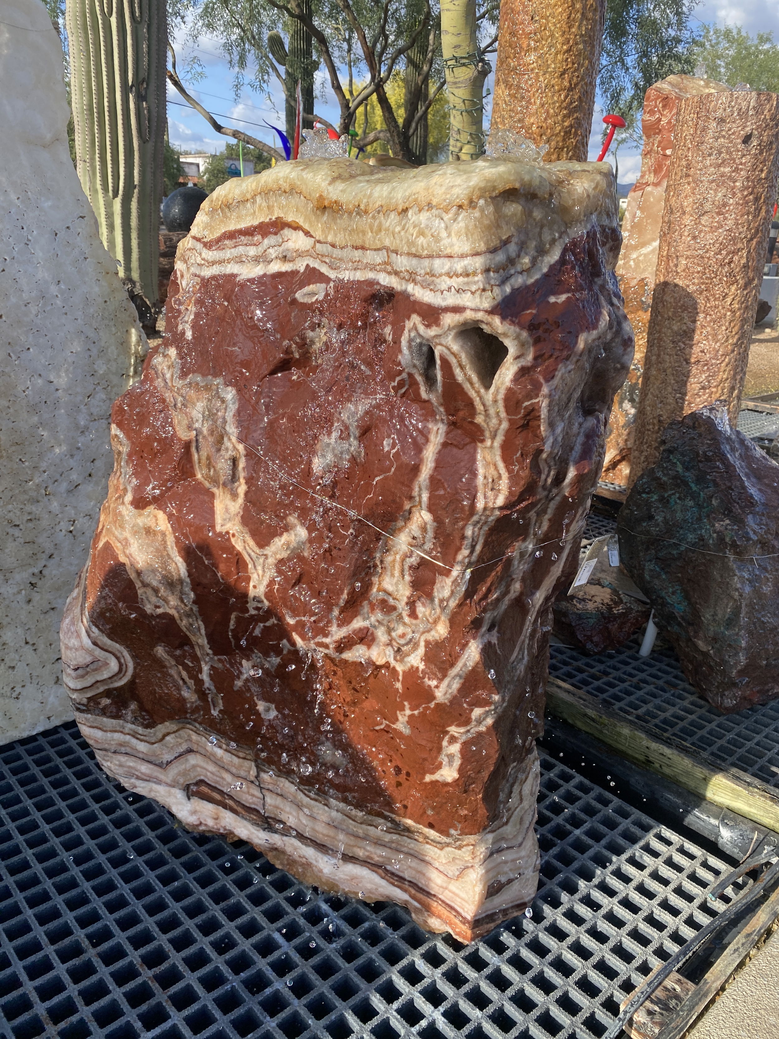 Serpentine Banded Onyx Fountain Rock is a beautiful natural stone fountain that brings a sense of tranquility to any outdoor space. Its unique banded pattern adds an aesthetically pleasing touch to your yard, garden or patio. Let Rare Earth Gallery’s white-glove service make your fountain dreams come true—simply choose your fountain, tell us where it goes, and we’ll handle the rest, from delivery to installation. IMPORTANT: the purchase price listed is for the FOUNTAIN ONLY and DOES NOT INCLUDE the cost of a basin, pump, parts or installation. Before purchasing a fountain online, we STRONGLY recommend you call us at (480) 575-4360 for a FREE consultation to discuss these additional costs and schedule a pre-site inspection. Also, free shipping does NOT apply to fountains, please call for a quote. Serpentine Onyx Fountain - Aqua Calcite Top With 2 Holes