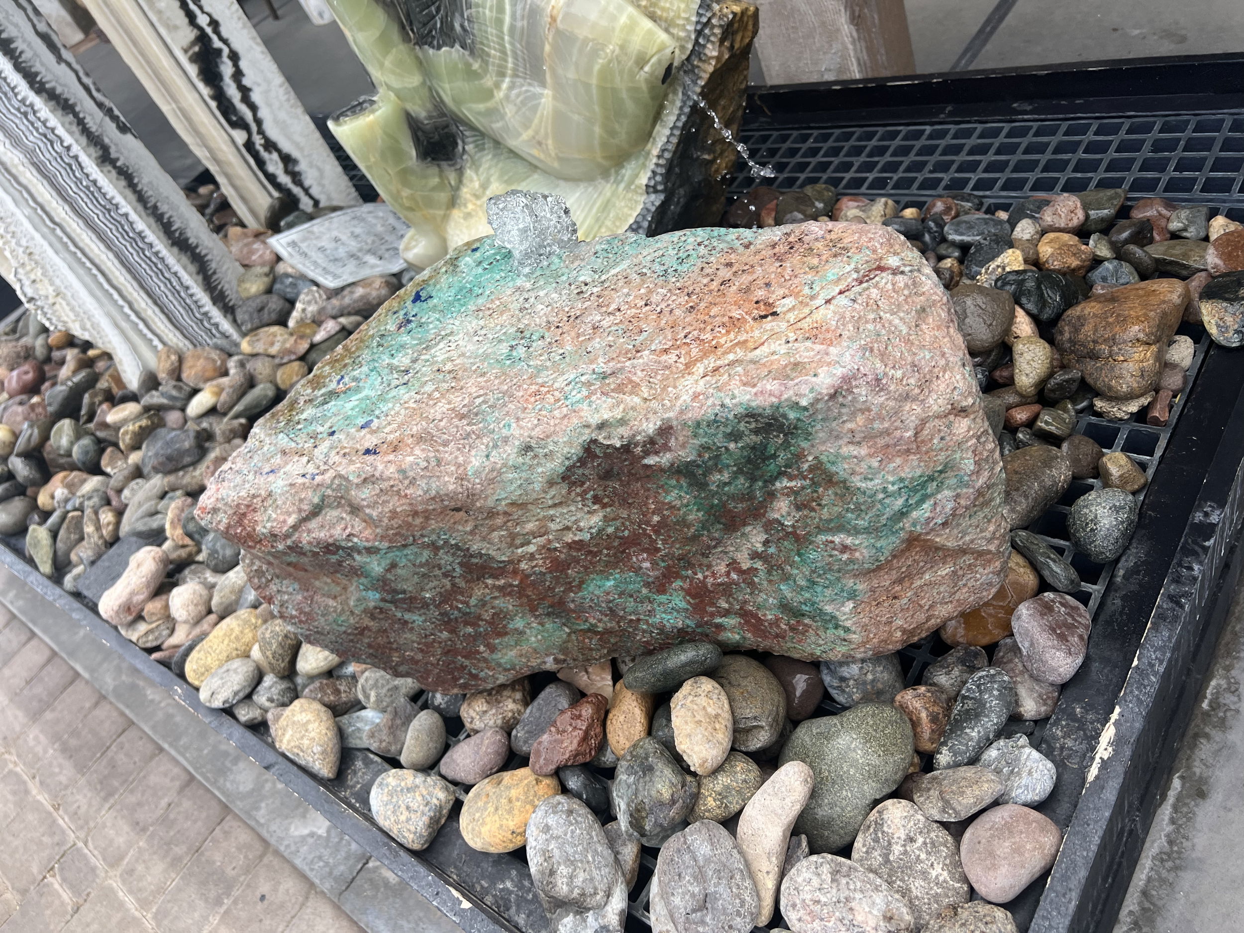 This Arizona Copper Ore Boulder Fountain adds a touch of serenity to any outdoor space with its Chrysocolla and Cuprite minerals. Enjoy the tranquility and aesthetic appeal of this unique water feature in your yard, garden, or patio. Let Rare Earth Gallery’s white-glove service make your fountain dreams come true—simply choose your fountain, tell us where it goes, and we’ll handle the rest, from delivery to installation. IMPORTANT: the purchase price listed is for the FOUNTAIN ONLY and DOES NOT INCLUDE the cost of a basin, pump, parts or installation. Before purchasing a fountain online, we STRONGLY recommend you call us at (480) 575-4360 for a FREE consultation to discuss these additional costs and schedule a pre-site inspection. Also, free shipping does NOT apply to fountains, please call for a quote. Arizona Copper Ore Boulder Fountain - Chrysocolla & Cuprite Low & Elongated