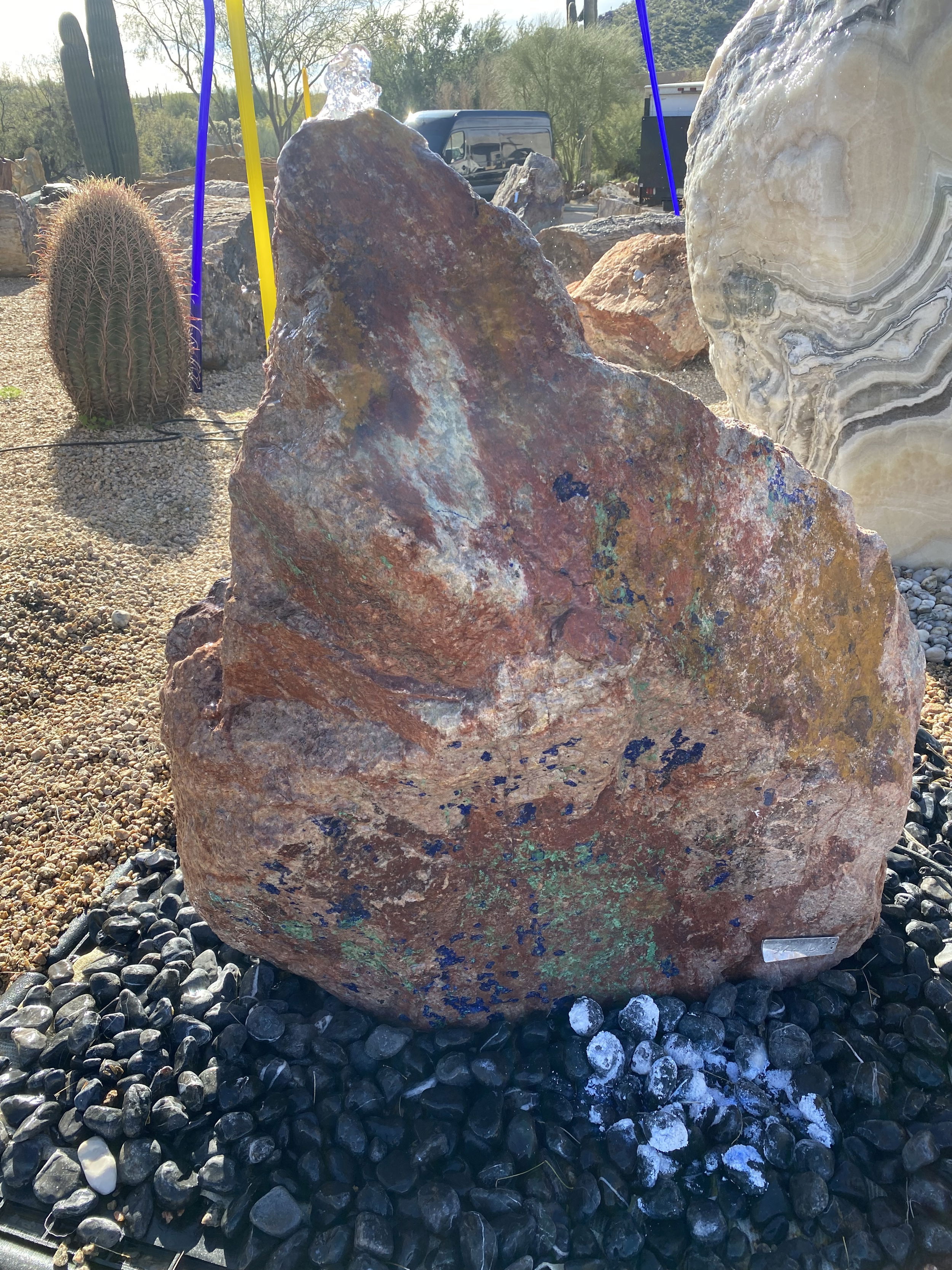 Introducing the captivating Red Cuprite with Azurite Malachite Copper Ore Boulder Fountain. This stunning piece effortlessly brings tranquility and enhances the aesthetic appeal of your yard, garden, or patio. With its unique combination of colors and textures, it is a perfect addition to create a serene and captivating outdoor space. Let Rare Earth Gallery’s white-glove service make your fountain dreams come true—simply choose your fountain, tell us where it goes, and we’ll handle the rest, from delivery to installation. IMPORTANT: the purchase price listed is for the FOUNTAIN ONLY and DOES NOT INCLUDE the cost of a basin, pump, parts or installation. Before purchasing a fountain online, we STRONGLY recommend you call us at (480) 575-4360 for a FREE consultation to discuss these additional costs and schedule a pre-site inspection. Also, free shipping does NOT apply to fountains, please call for a quote. Red Cuprite With Azurite Malachite Copper Ore Boulder Fountain