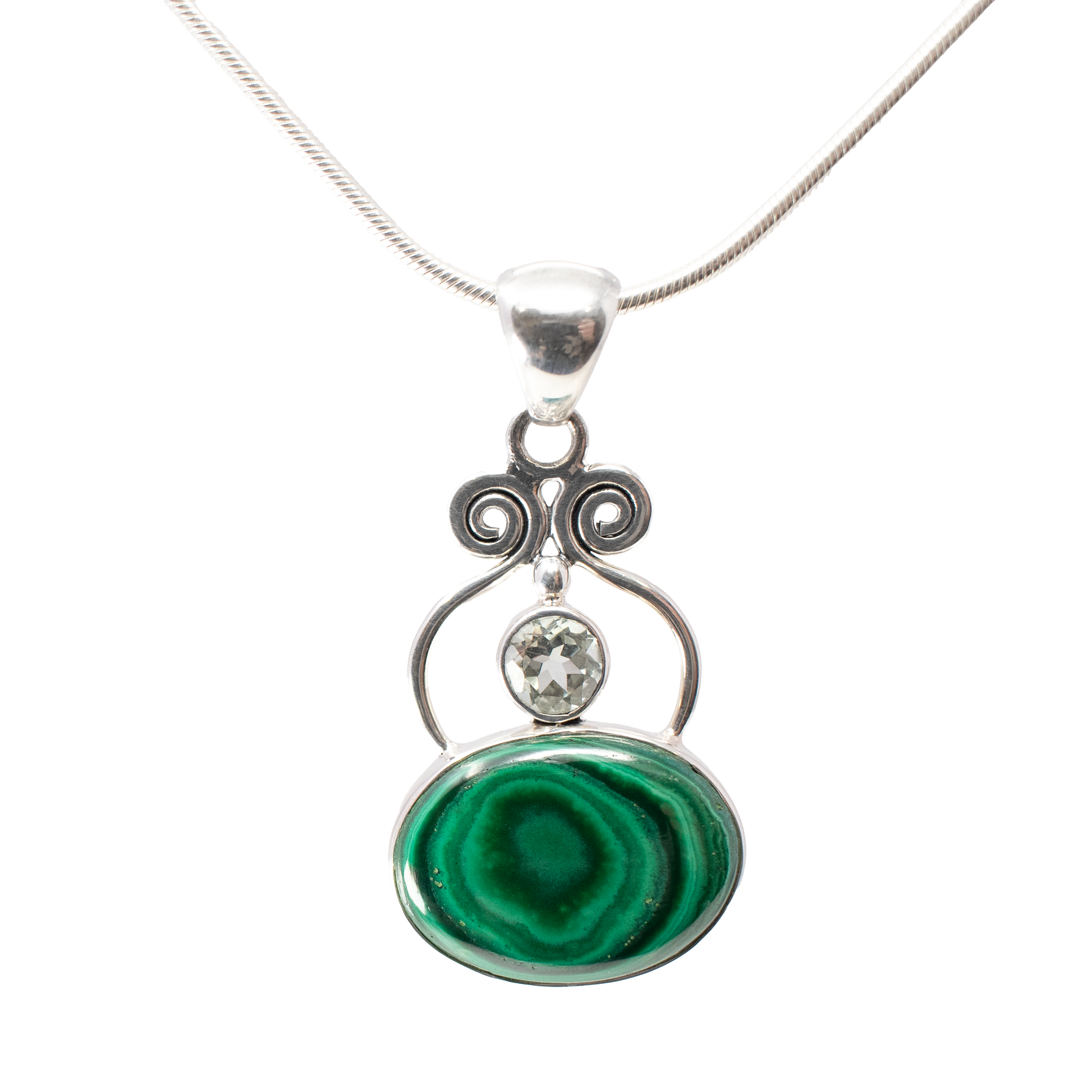 Elevate your jewelry collection with our exquisite Malachite Pendant, a true masterpiece of artisan craftsmanship and timeless elegance. This stunning piece features an enchanting oval cabochon of rich green malachite, renowned for its striking bands and swirls that evoke the beauty of nature. The malachite's deep, varying hues tell a story of luxury and earthiness, making it a captivating centerpiece for any attire.Enhancing the pendant's allure is a round, faceted blue topaz, carefully selected for its brilliant clarity and vibrant color. The topaz adds a touch of sparkling sophistication, contrasting beautifully with the lush green malachite. Set meticulously in 925 sterling silver, the topaz and malachite are cradled within intricate bezels and swirls, showcasing the silversmith's attention to detail and dedication to quality. Malachite Pendant - Oval Cabochon with Faceted Blue Topaz Round Set in 925 Sterling Silver Bezels & Swirls