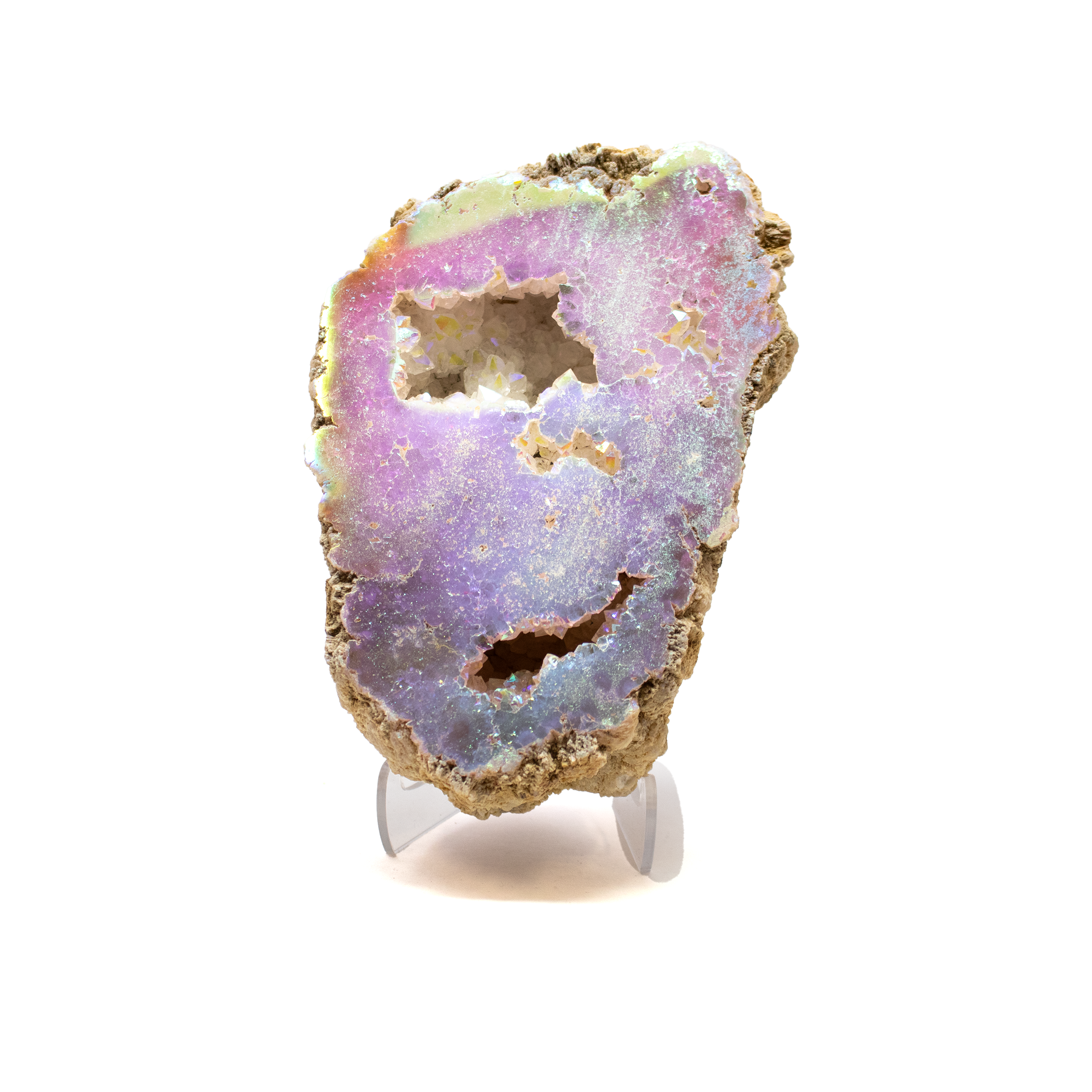An ethereal fusion of Earth and sky, this Silicon Oxide Geode with Cut Face on Lucite Stand captures the quiet grandeur of ancient stone touched by celestial light. Its exposed crystalline interior, revealed through expert cutting and polishing, shimmers with intricate formations of silicon oxide quartz—each one a frozen breath of geological time. Transformed by an Angel Aura finish, the geode glows with an iridescent sheen, where soft pastels ripple like light across water, evoking angel wings or the edge of a dream.Poised on a clear Lucite pedestal, the geode appears to hover in space—an elegant contrast between the raw and the refined. The stand invites light to move freely around the specimen, illuminating every glittering surface and amplifying its otherworldly presence. Whether displayed as a meditative focal point, a sculptural accent, or a treasured addition to a collector's cabinet, this piece is a harmonious dialogue between nature’s artistry and human reverence. Silicon Oxide Geode with Cut Face on Lucite Stand